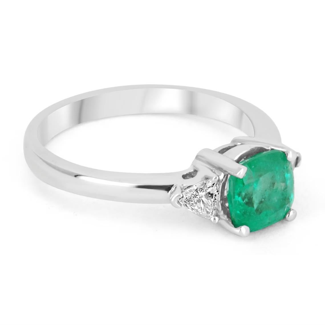 A classic Colombian emerald and diamond three-stone ring. Dexterously crafted in gleaming 18K white gold this ring features a natural Colombian emerald, cushion cut from the famous Muzo mines. Set in a secure four prong setting, this extraordinary