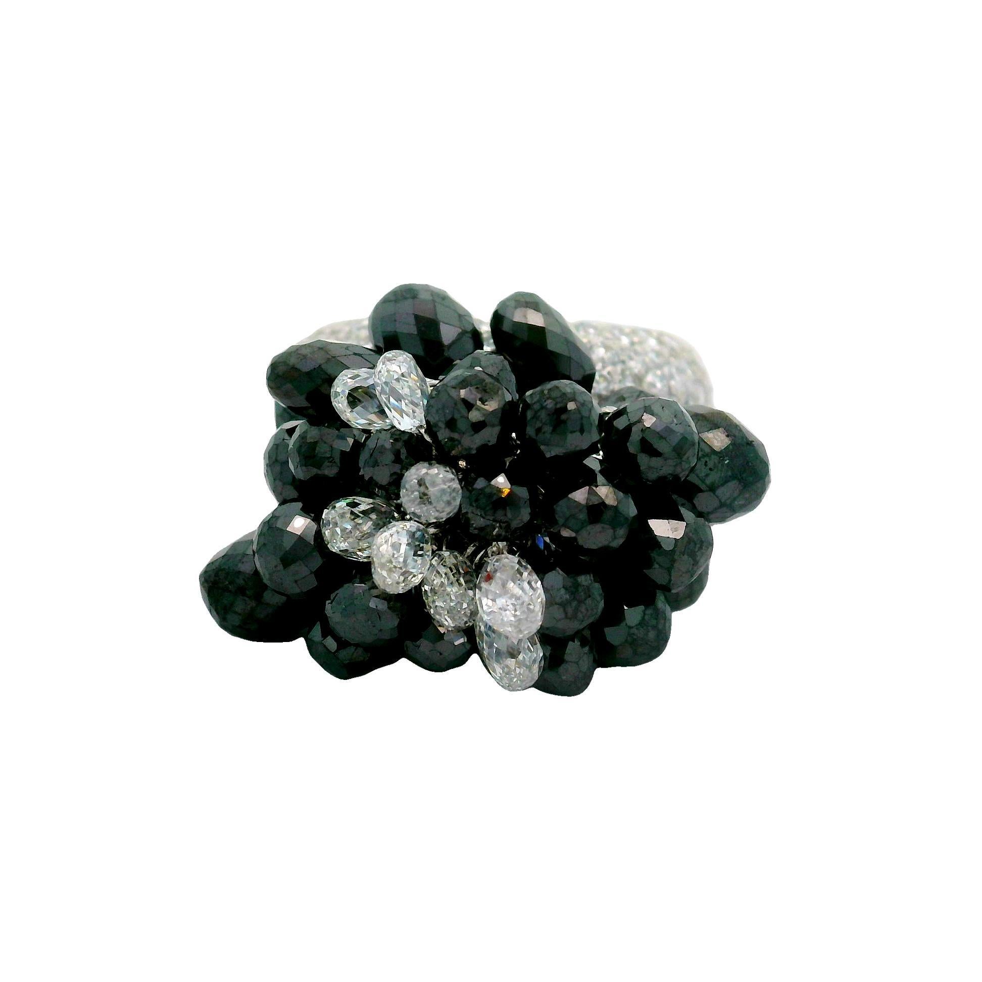 Une bague amusante et excitante présentant des pompons de fins diamants briolettes, à la fois noirs et blancs. Les glands se déplacent librement sur l'anneau lorsqu'on le bouge, ce qui confère à la pièce son mouvement et sa sonorité. Le bracelet est