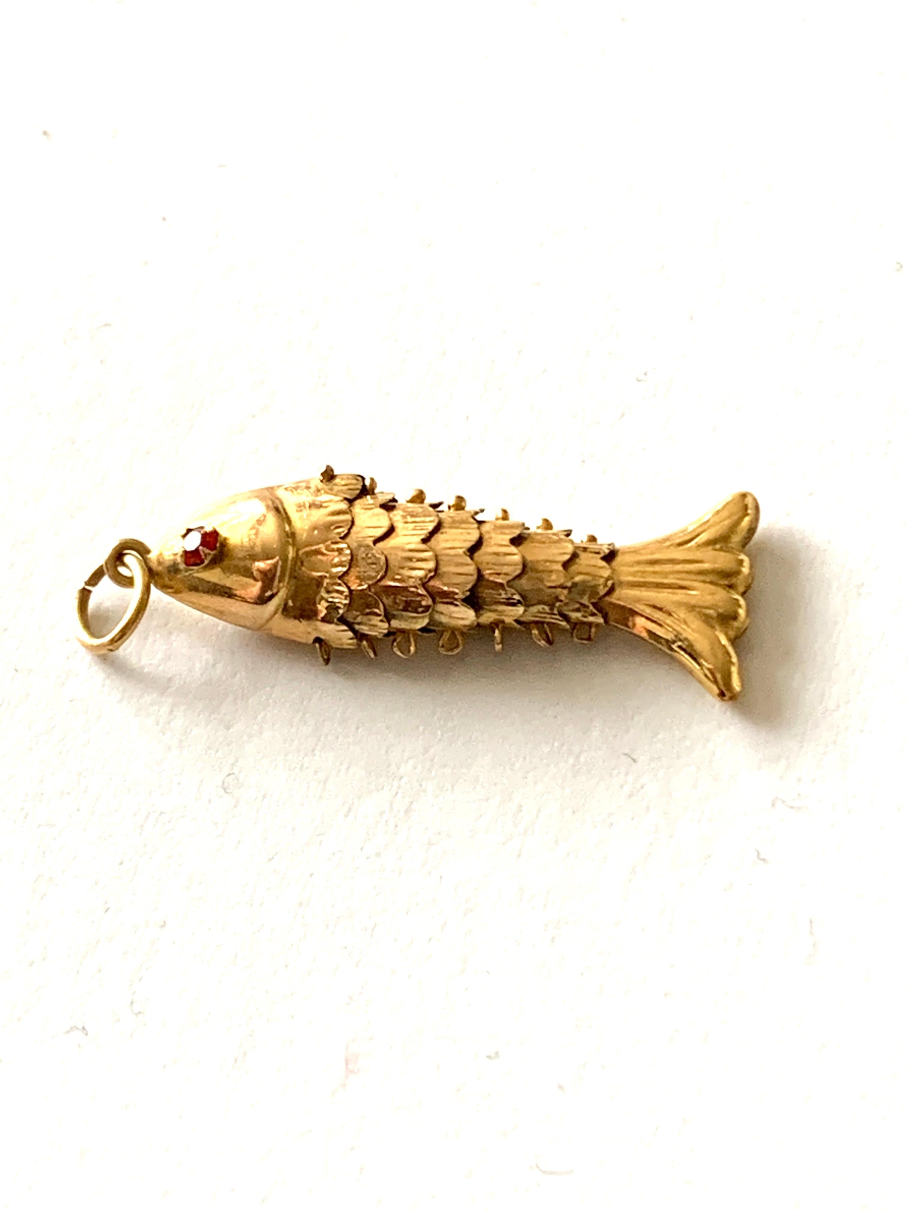 14ct 585 Gold Gelenkiger Fisch 
mit einem unbekannten roten Edelsteinauge
Gestempelt 14k an zwei Stellen
Epoche 1970er Jahre
Heller Schwanz
Größe 30mm x 7mm x 3mm (inkl. Sprungring)
Gesamtgewicht 1,14 Gramm .