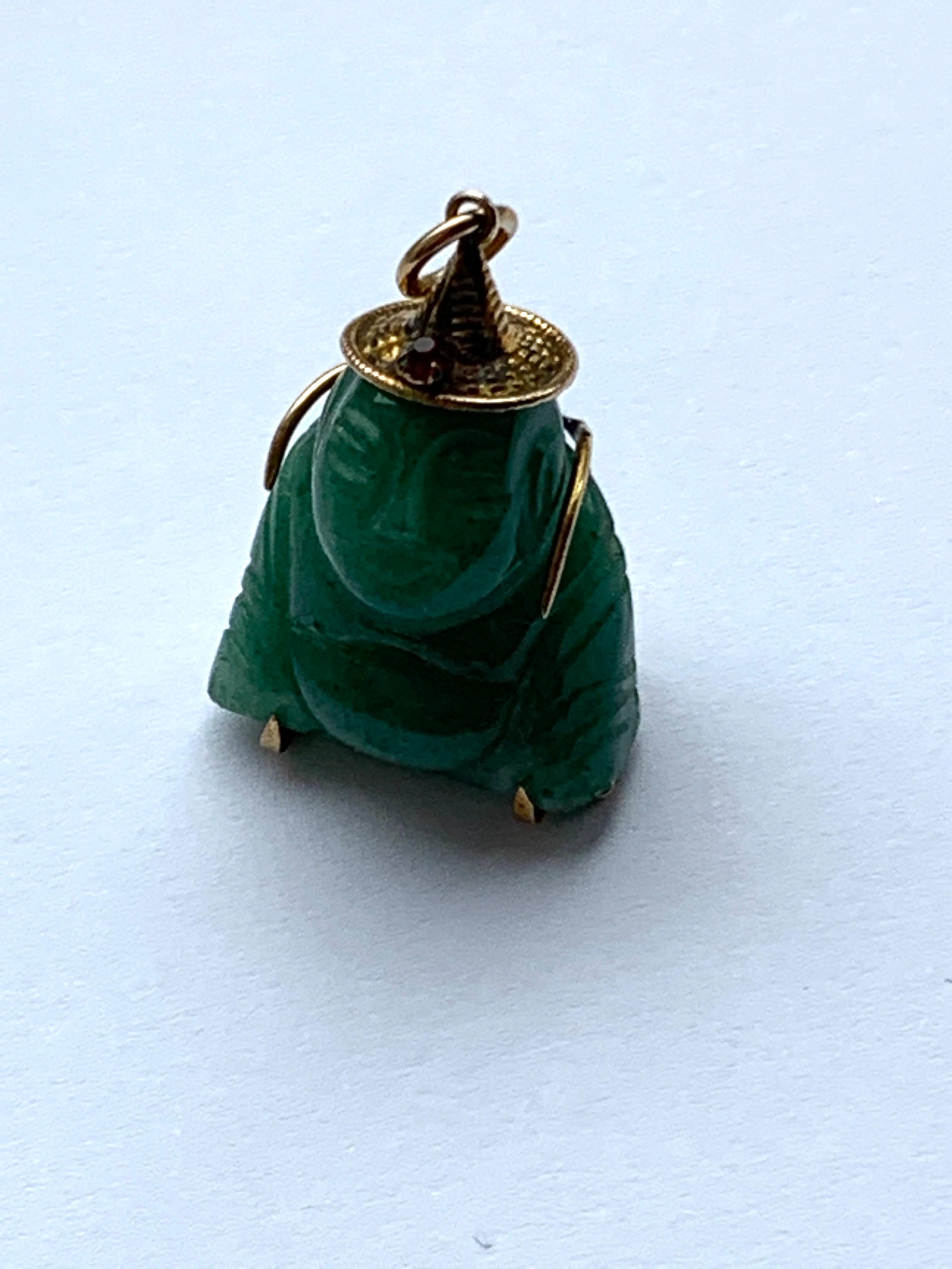 Mid Century Circa 1950
Jade Buddha Pendant
with 14ct Gold hat and Back support
Unknown red gemstone in front of hat 
Size - 3cm x 2cm
(cm = centimeters)
Stamped - 14k (fading mark)
Weight - 9.17 grams