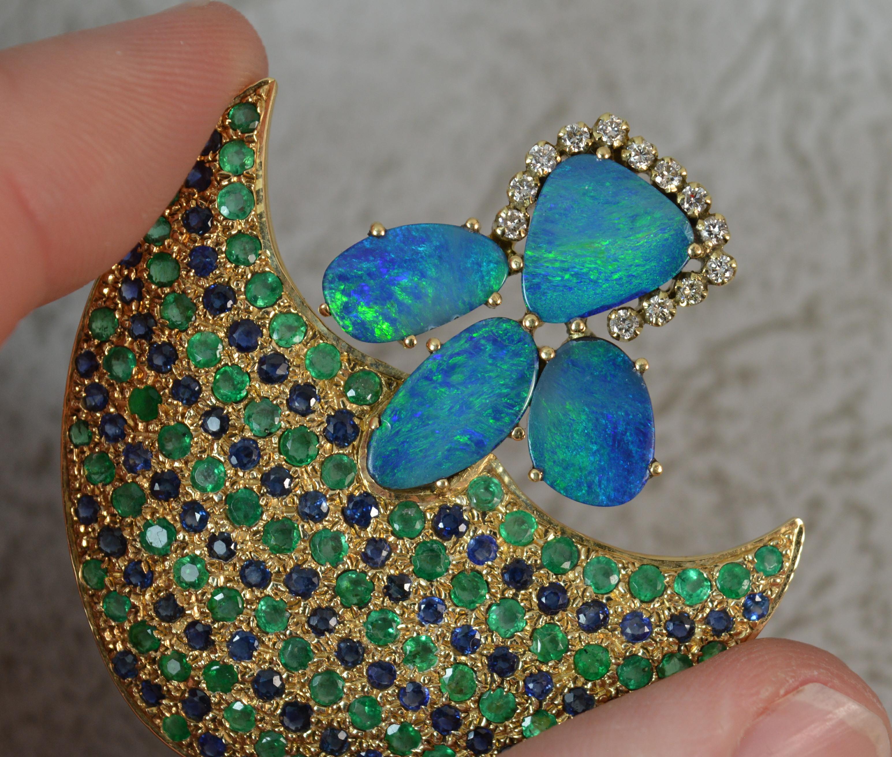 A stunning 14 carat gold brooch.

Unusually shaped, perhaps an arrow, or even a fish.

Set with many round cut rows of alternating green emeralds and blue sapphires to the main body. The end set with four opal doublets which are surrounded by small