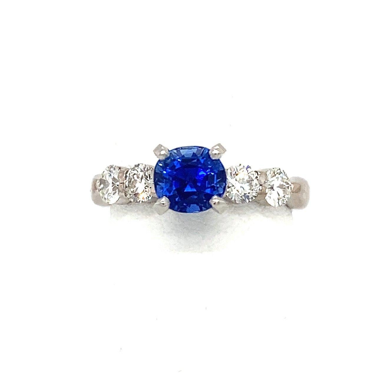 This ring features an untreated 1.4CT vivid blue Sri Lankan sapphire with a GIA certification. The sapphire is flanked by four round bright, sparkling diamonds that total approximately .64CT, F-G Color, VS Clarity. The sapphire and diamonds are set