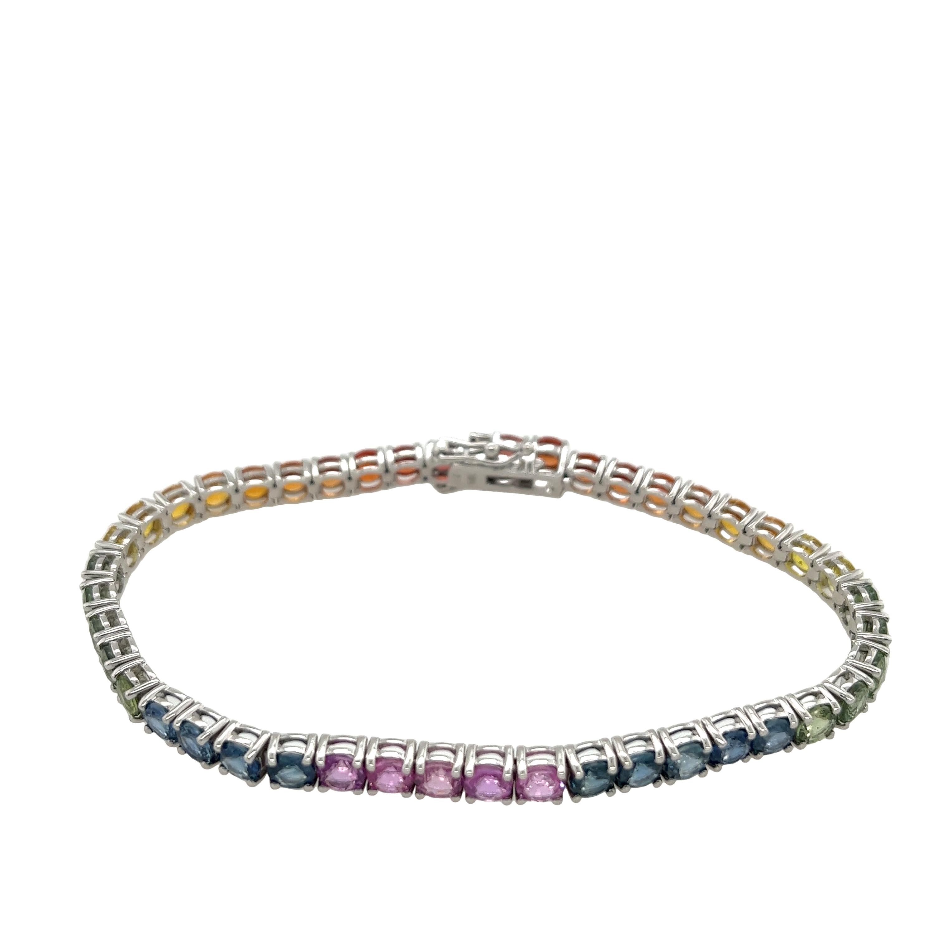 Offrez-vous une élégance intemporelle avec notre exquis bracelet de tennis en or blanc 14ct à saphirs naturels et arc-en-ciel. Fabriqué à la perfection, ce bracelet présente une étonnante gamme de saphirs naturels, chacun délicatement serti dans de