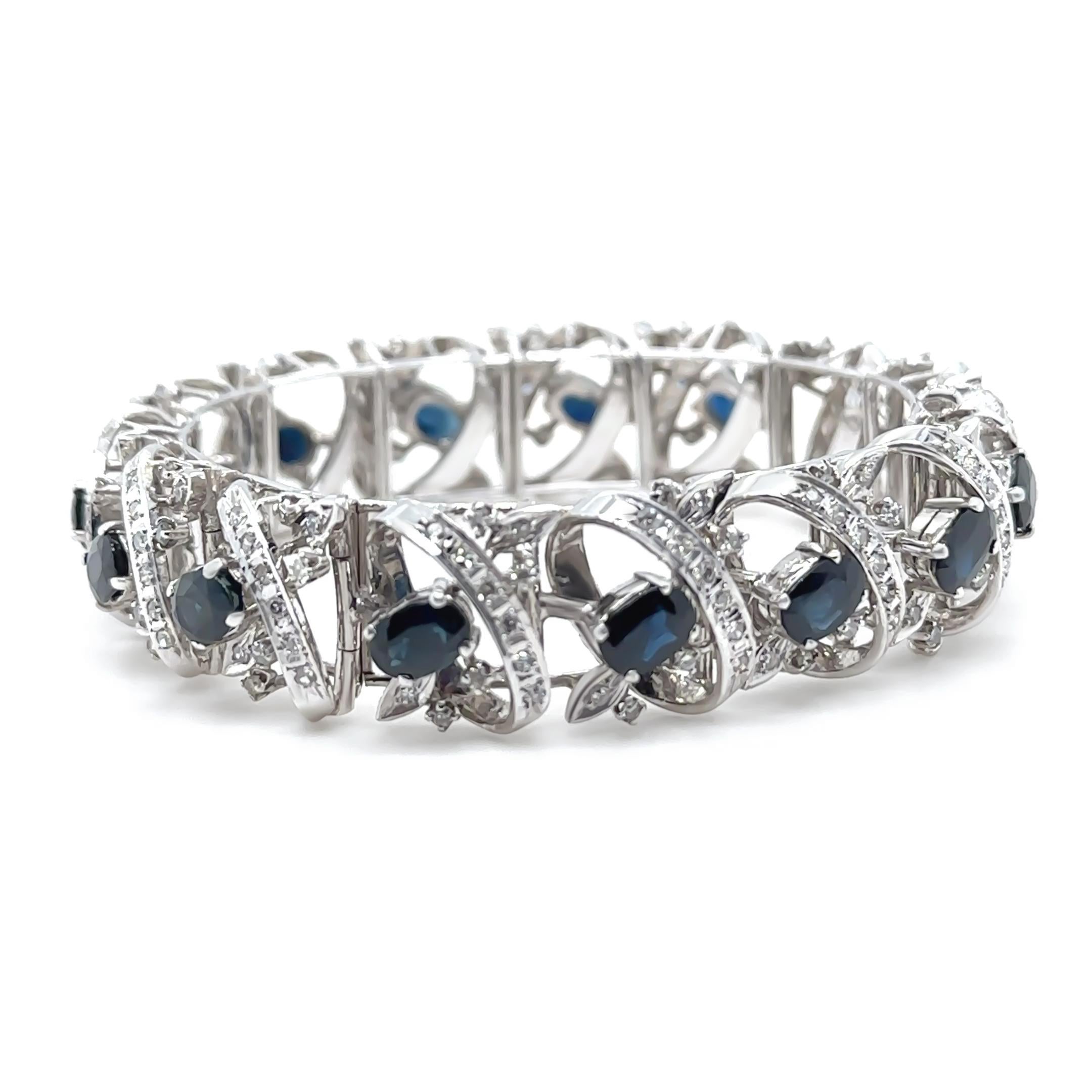 This showstopping sapphire and diamond bracelet is crafted in 14ct white gold and features a wide, articulated cluster design. At its centre are 15 raised, oval-cut natural Australian blue sapphires, each four-claw set, displaying rich, deep hues.