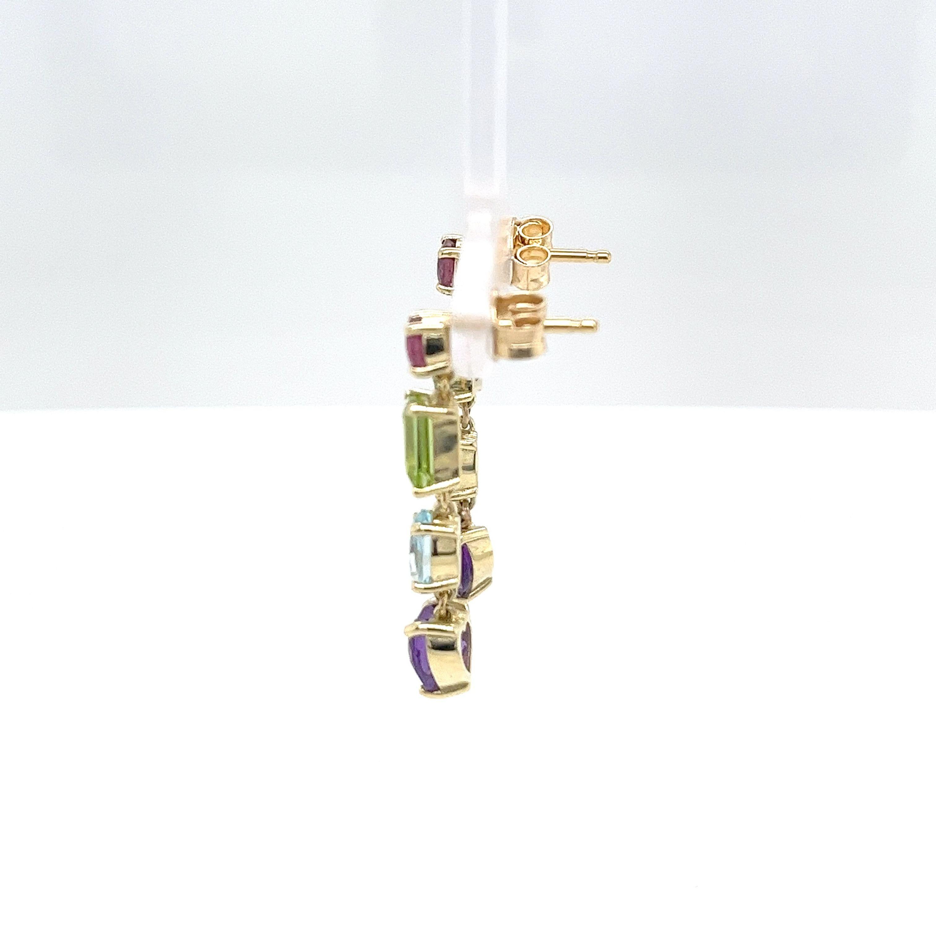 These 14ct yellow gold drop earrings showcase a beautiful arrangement of multi-coloured gemstones, including a heart-shaped amethyst, rectangular peridots, aquamarine, and ruby. 
A vibrant and stylish design, perfect for adding elegance and a splash