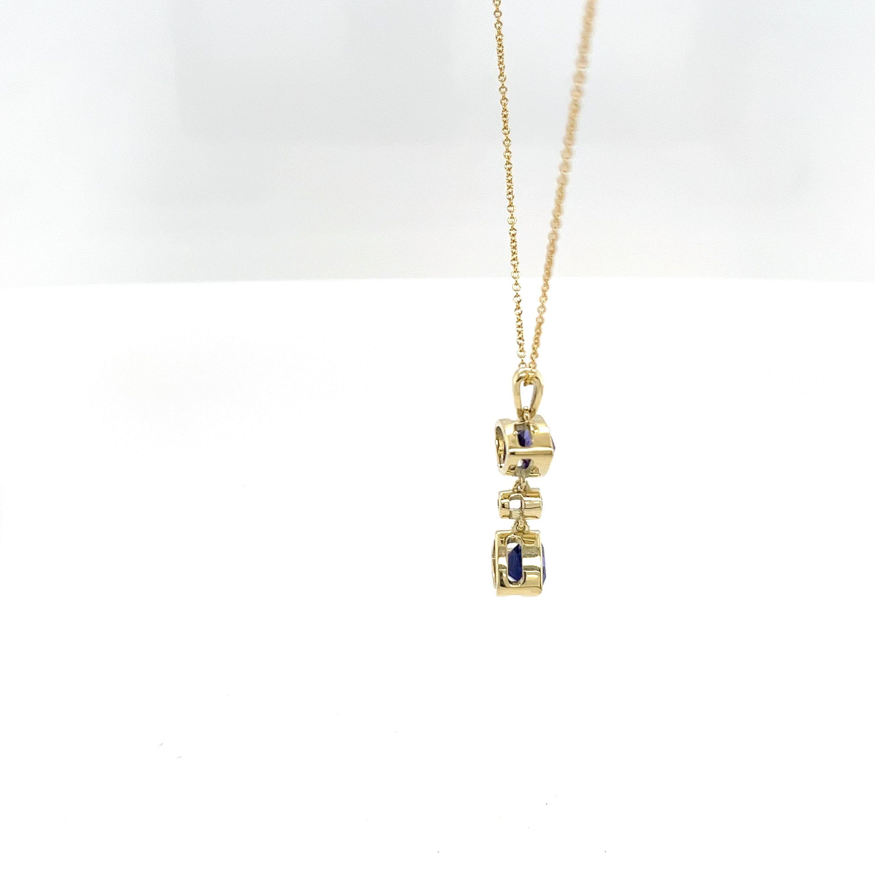 Rehaussez votre collection de bijoux avec cet exquis pendentif en or jaune 14ct, orné de tanzanites et de diamants, joliment associé à une chaîne en or 18ct. Doté de deux magnifiques tanzanites en forme de triangle et d'un diamant étincelant en son