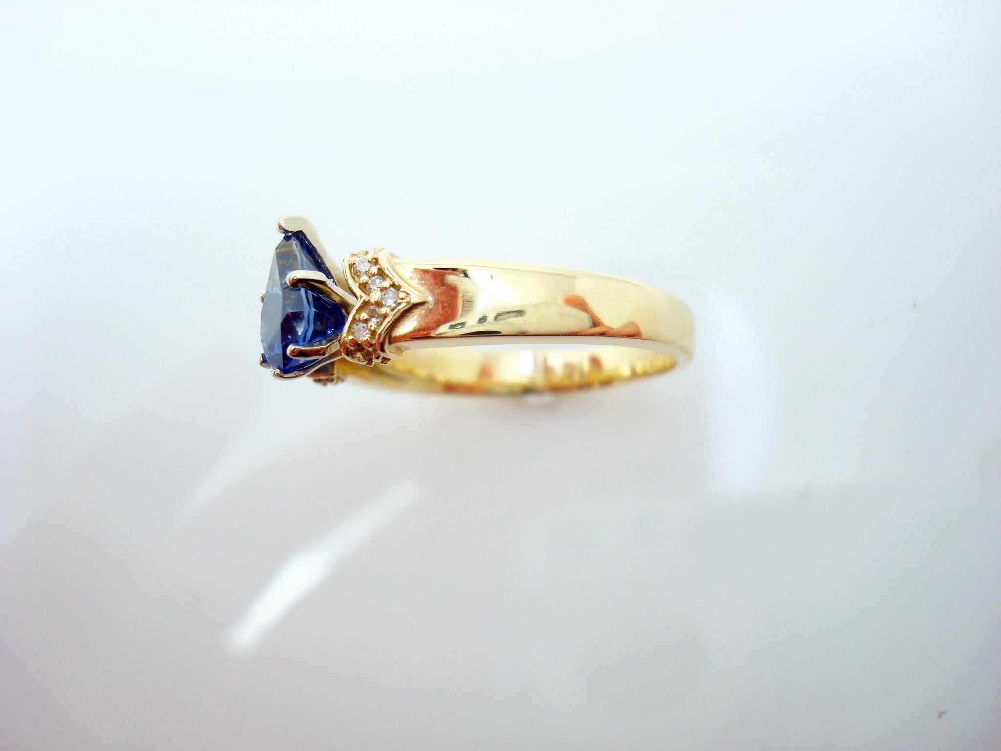 14K yellow gold sapphire & diamond ring featuring a royal blue pear shape sapphire weighing 1.28 carats. The sapphire is accented by a wide band set with with small round diamond accents.  The Sapphire measures 8mm x 5.5mm and the Diamonds are 1mm. 