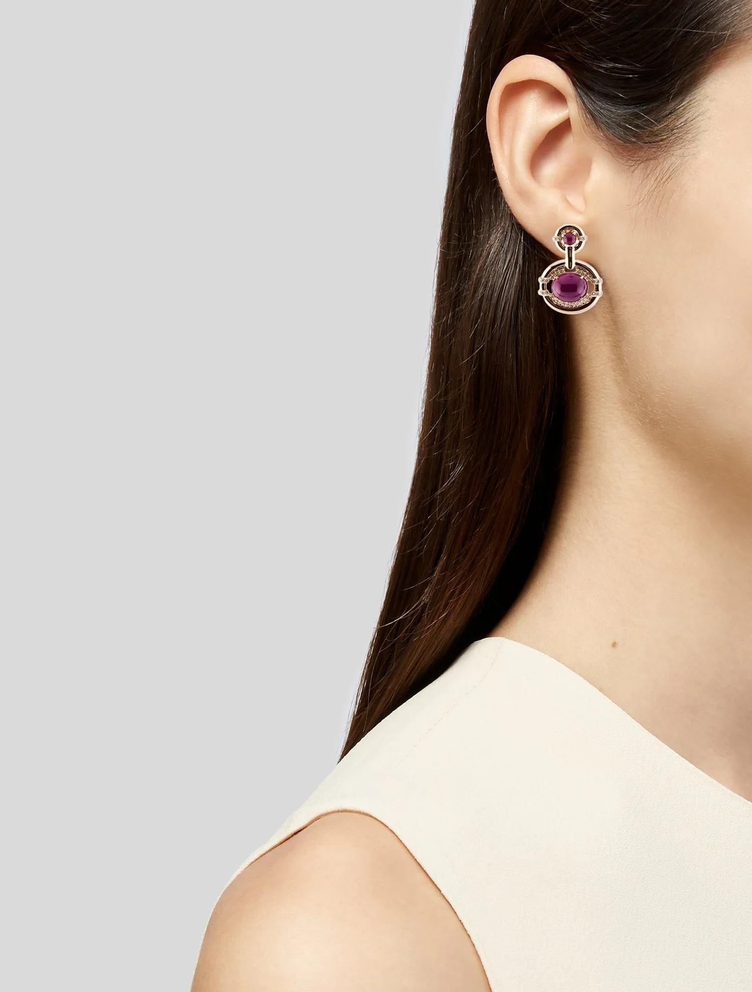 These exquisite 14K yellow gold drop earrings feature a stunning combination of cabochon-cut rubies and brilliant diamonds. The focal point of these earrings is the pair of 0.78 carat round ruby cabochons, set prominently to catch the eye.