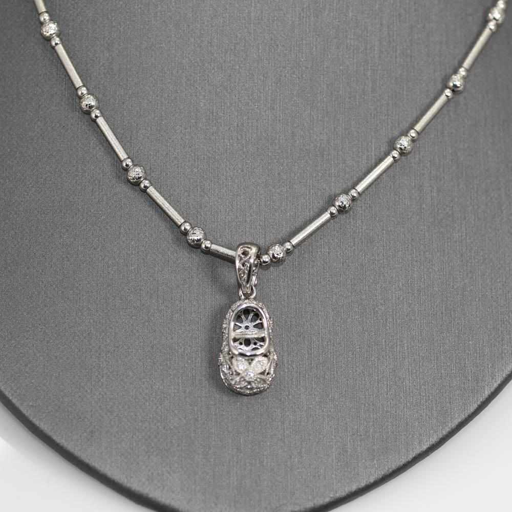 Collana in oro bianco 14k con ciondolo a forma di scarpa con diamante 18k.
La catena ha un peso di 11,7 grammi.
La scarpa reca il timbro 18k all'interno della chiusura e pesa 4,8 grammi.
I diamanti del pendente sono tagli tondi brillanti, 0,13