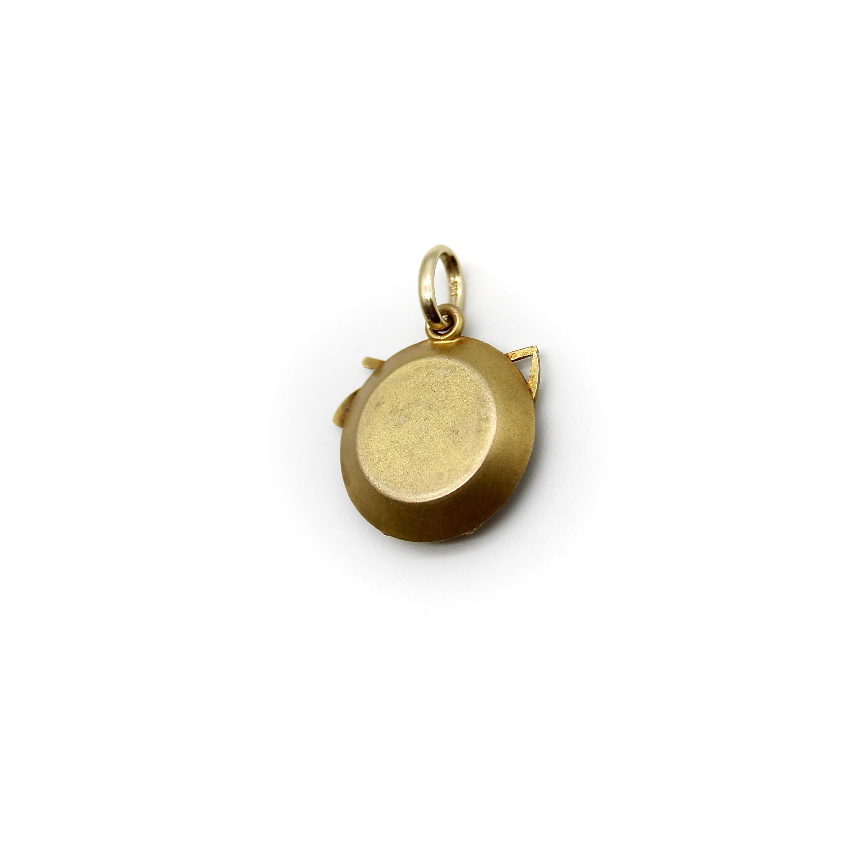 This 14k gold charm is a three dimensional rendering of a prospector’s tools. A shovel and pick-axe make a crisscross above a rope pulley system. Beneath them—as if underground—are several tiny gold nuggets, waiting to be mined. Each element of the