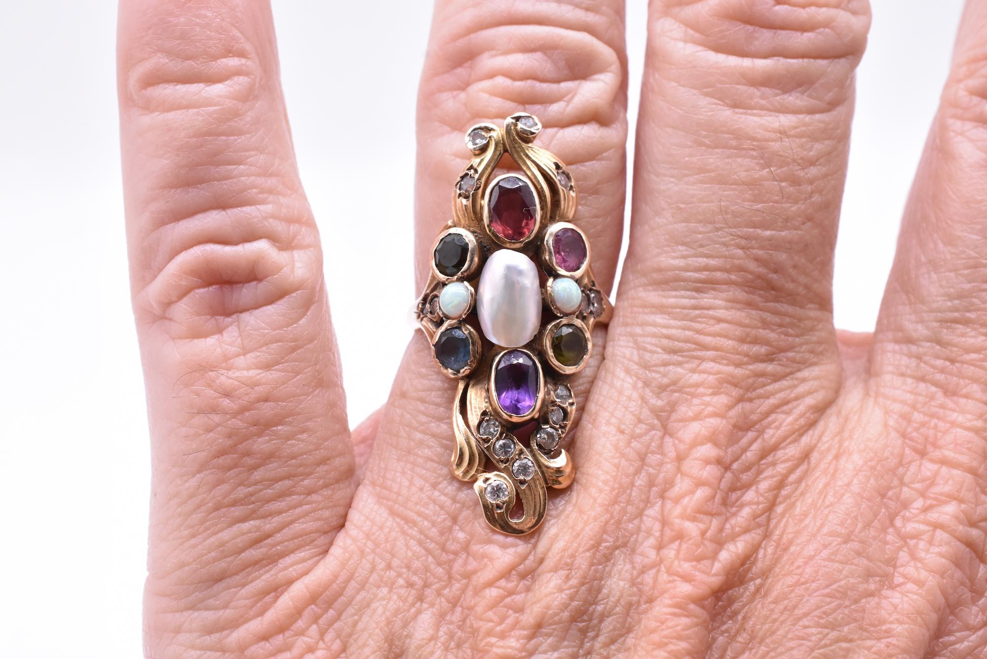 Circa 1900 colorful 14K American Art Nouveau ring with small diamond accent stones, and peridot, opal, garnet, amethyst, and aqua stones encircling the larger freshwater pearl at the center. The complimentary gemstones, graceful gold metal