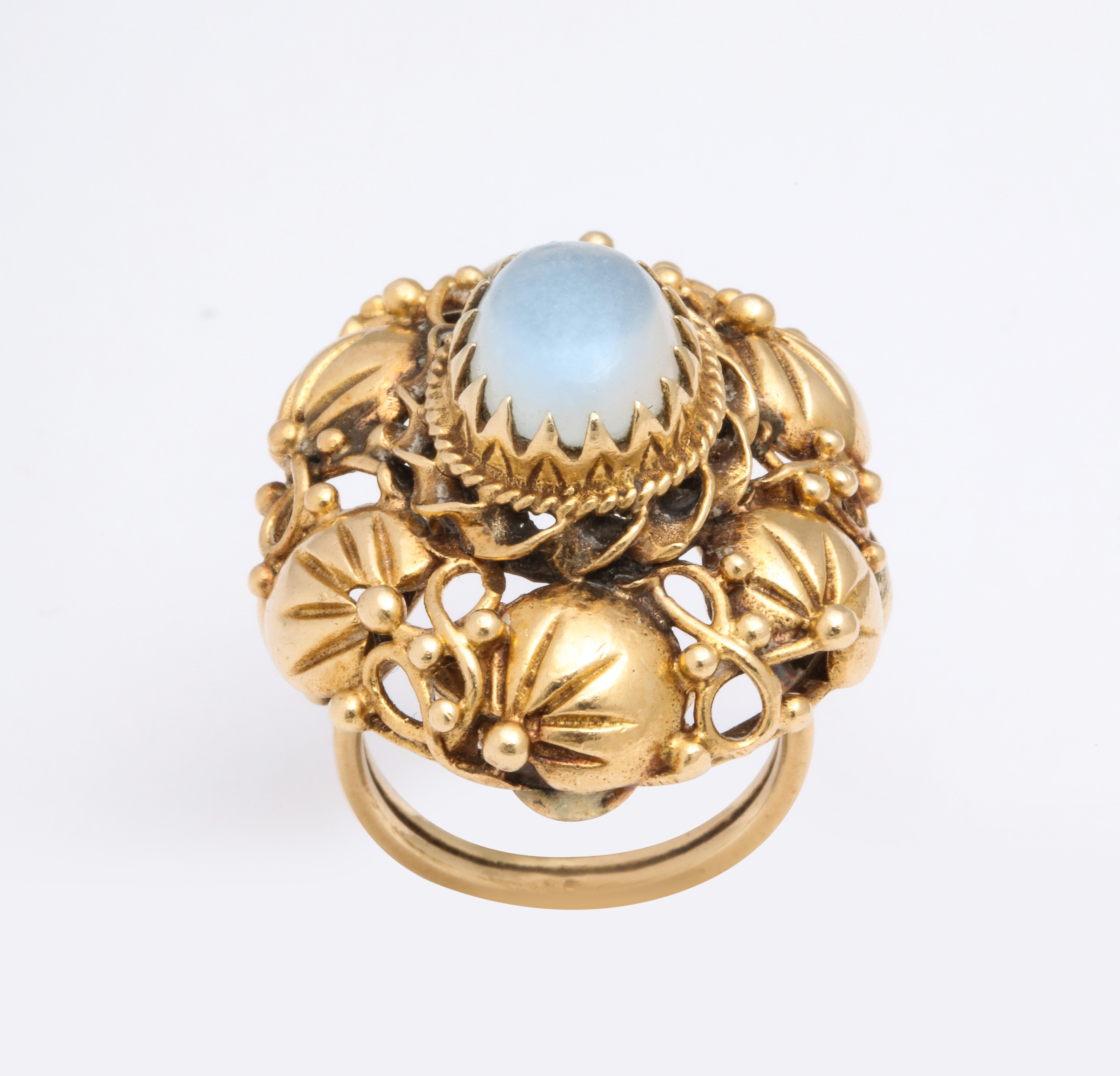 A cluster of 14k gold blossoms  surround a center cabochon moonstone. Beautifully crafted with a nouveau style