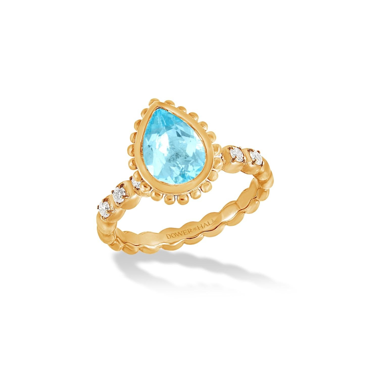 This dramatic and directional ring is set with a pear cut Blue Topaz in 14k yellow gold featuring granulated balls around the outside of the rub-over setting and with diamonds claw set in the dotty style band. Inspired by creatures of the coral