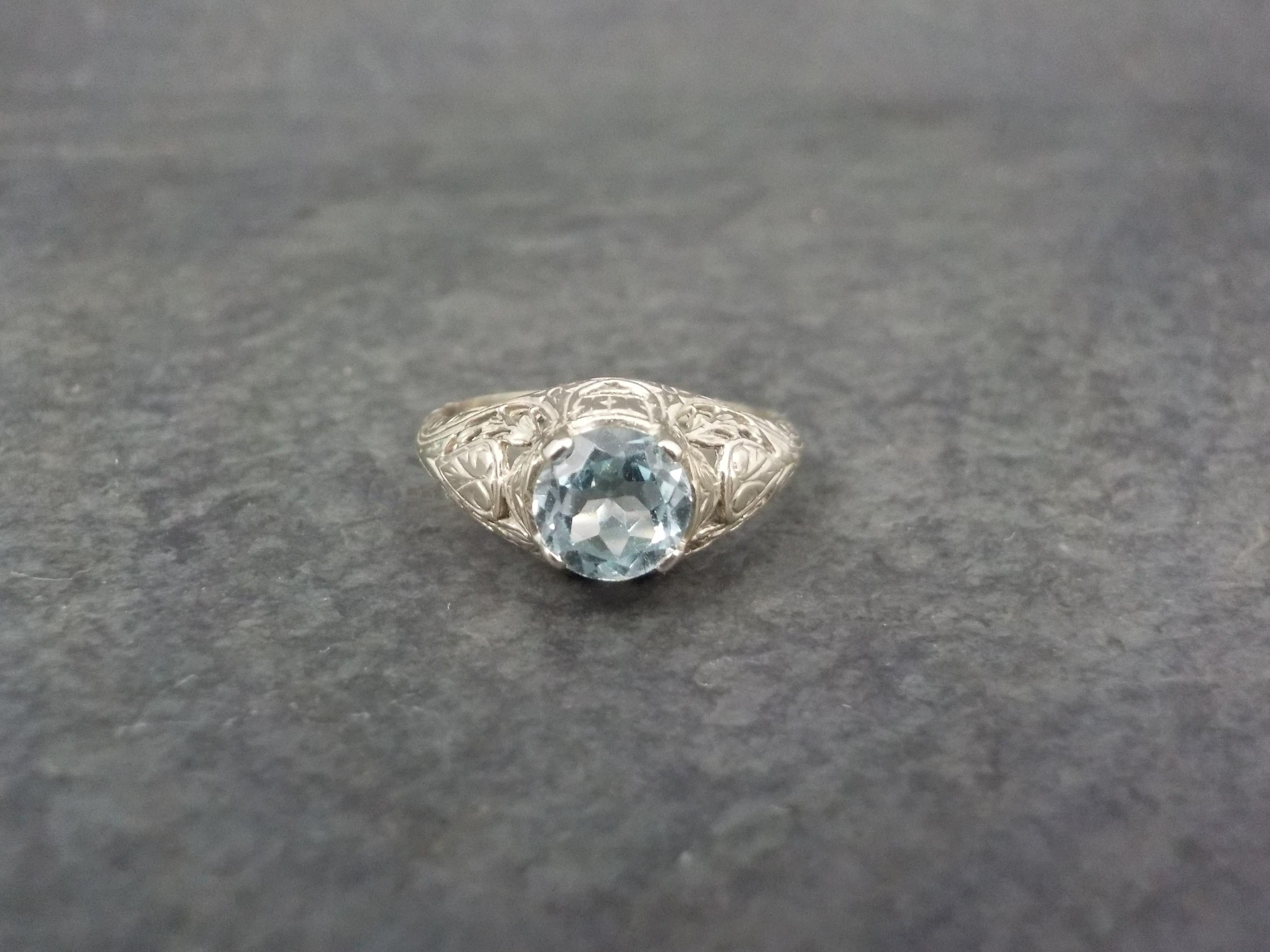 This gorgeous Art Deco ring is 14k white gold.
It features a delicate filigree design with a 6mm blue topaz gemstone.
The face of this ring measures 5/16 of an inch north to south with a rise of 6mm off the finger.
Size: 5
Marks: 14K
Condition: