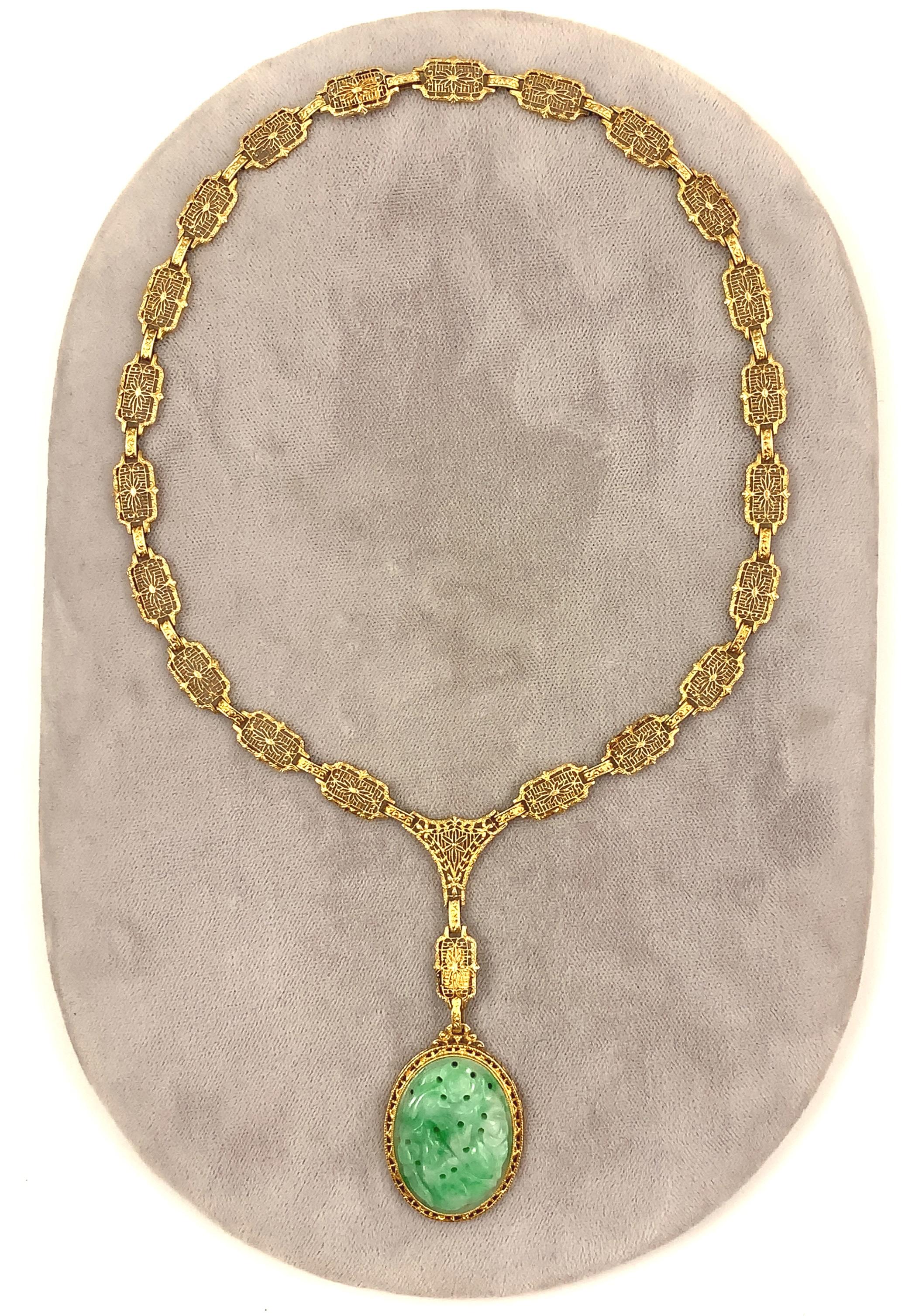 Art Deco 14K yellow gold pendant featuring a beautiful carved oval jadeite jade. Includes GIA report #6223435637 stating translucent green A jade, not dyed.  The jade measures 26.80mm x 20.20mm x 4.40mm. The necklace is comprised of 23 cast filigree