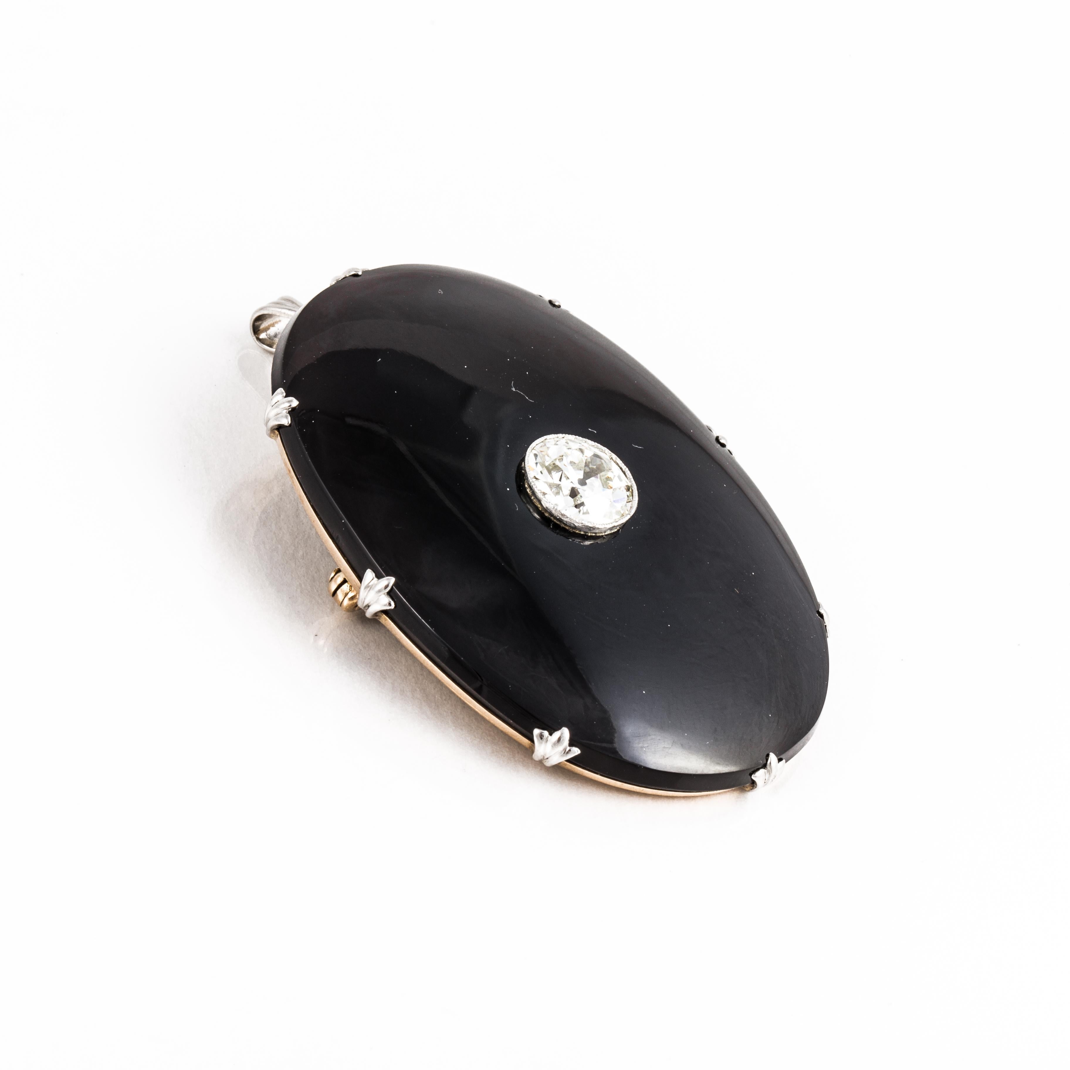 Art Deco brooch/pendant composed of 14K yellow and white gold with a large oval cut onyx featuring a round white zircon in the center.  The piece is marked 