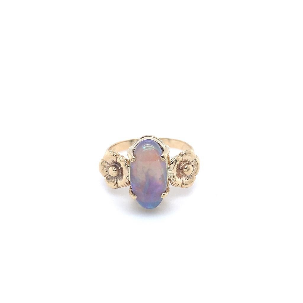  14K yellow gold ring featuring a natural earth mined solid black opal accented by flower blossoms. The opal is a long oval cabochon measuring 13.6mm x 7.1mm and weighing 3 carats. The opal has dark grey body color with blue-green play of color. The