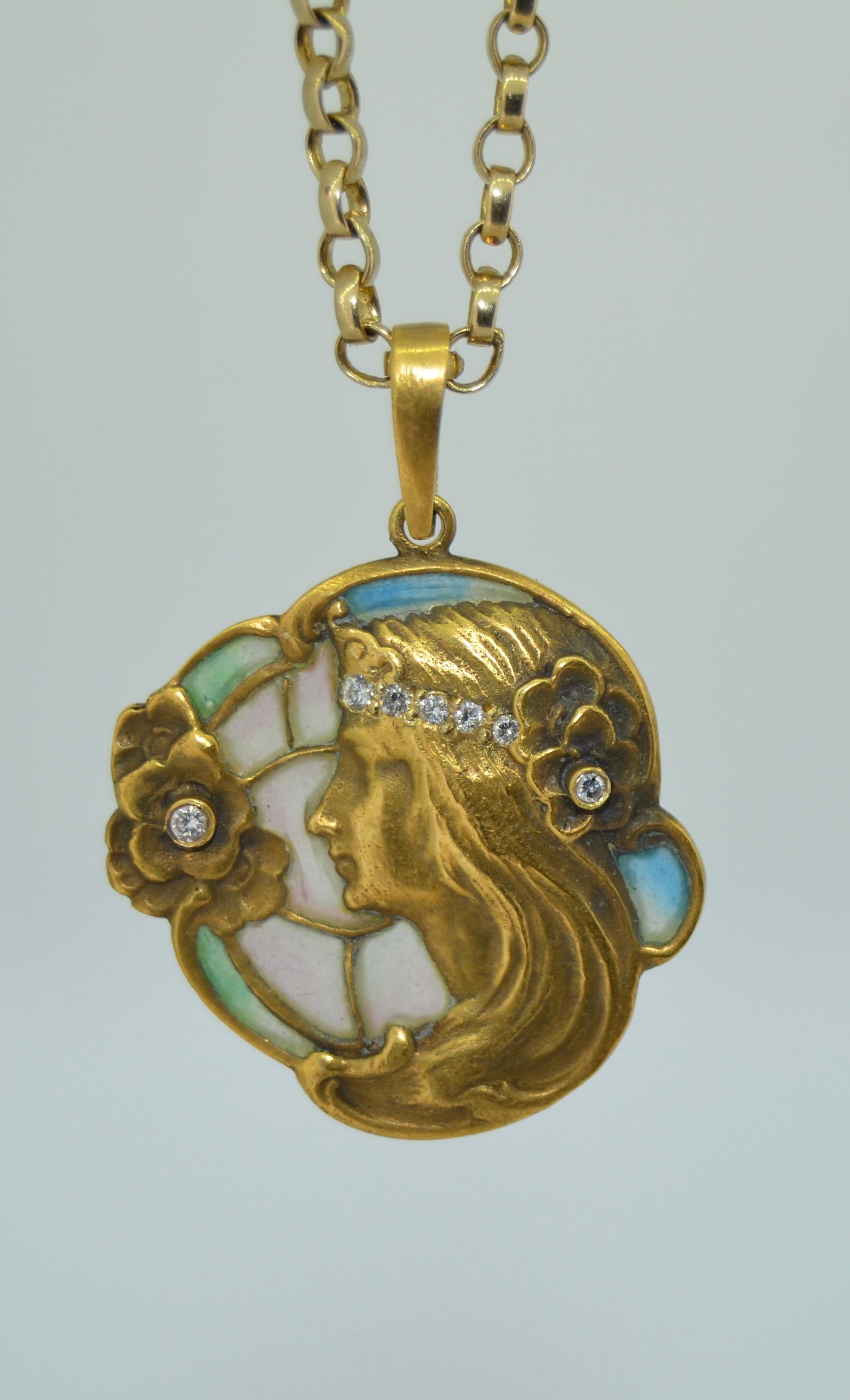 Dies ist ein prächtiger Plique-a-jour-Anhänger aus der Jugendstilzeit. Er ist aus 14 Karat Gelbgold mit Diamanten und Plique-a-Jour-Emaille gefertigt. 
Dieser Anhänger hat eine schöne pastellfarbene Emaille in Grün-Blau-Rosa. Die Jungfrau zeichnet