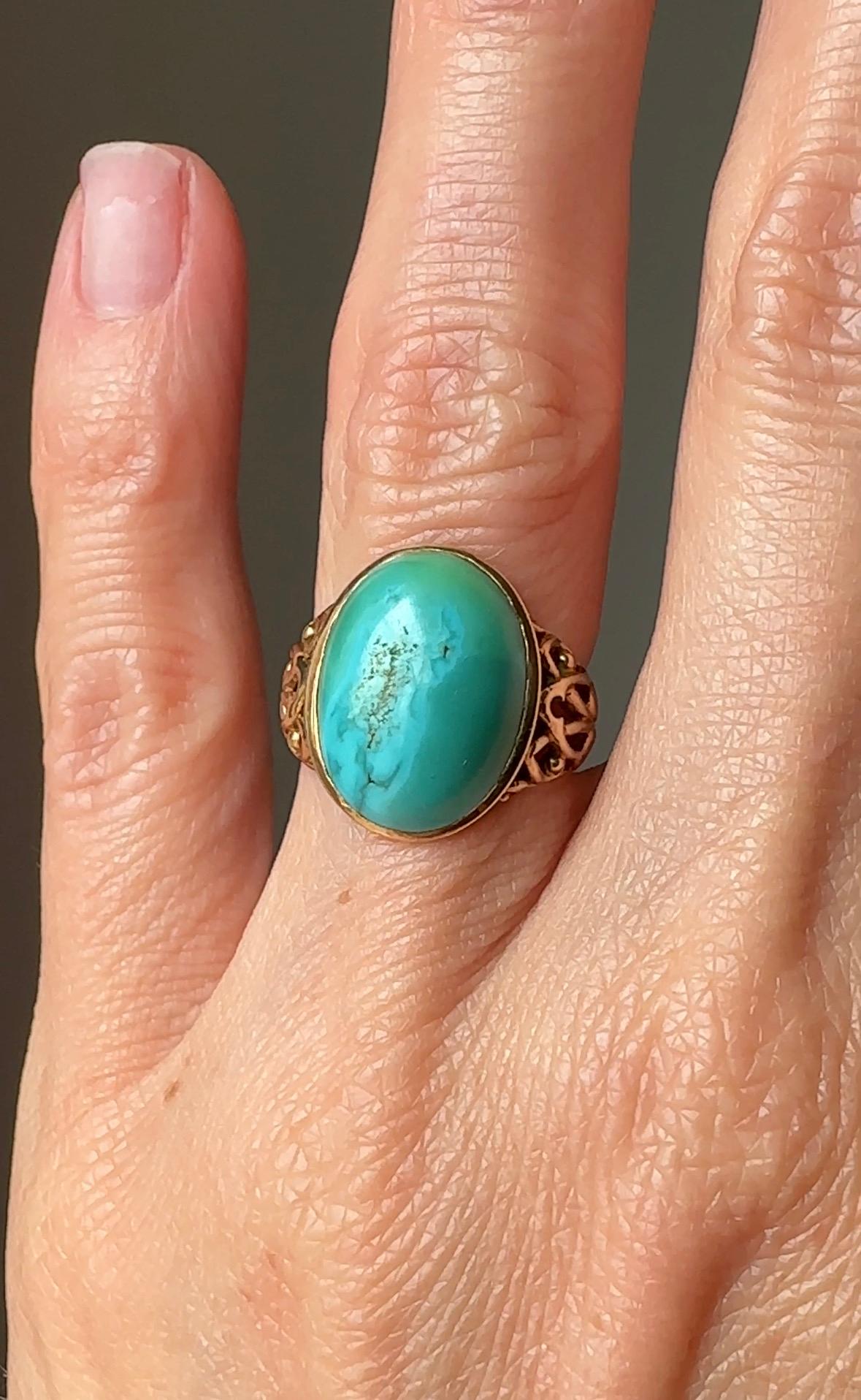 Dating to the turn of the 20th century, a bright variegated blue-green turquoise cabochon, perfectly presented by sculpted shoulders of a neoclassical scroll design.    Finely crafted in textured 14k yellow gold. A rare treasure. Currently a ring
