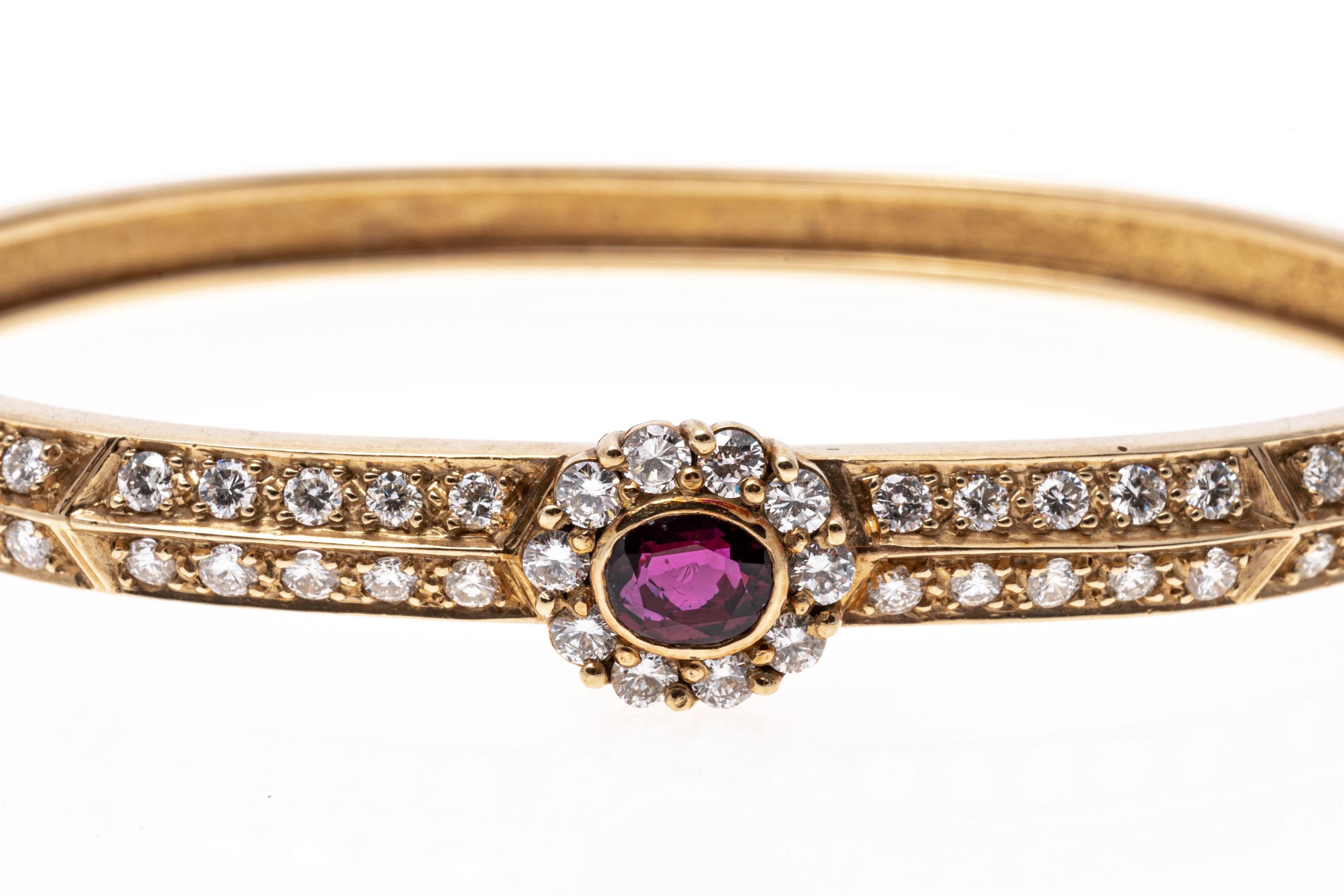 This charming 14K yellow gold bracelet displays two rows of round cut diamonds trailing across the band. Set over the band is an oval ruby framed within a halo of diamonds. Diamonds are approximately 1.5 TCW and the Ruby is approximately 0.5 cts.