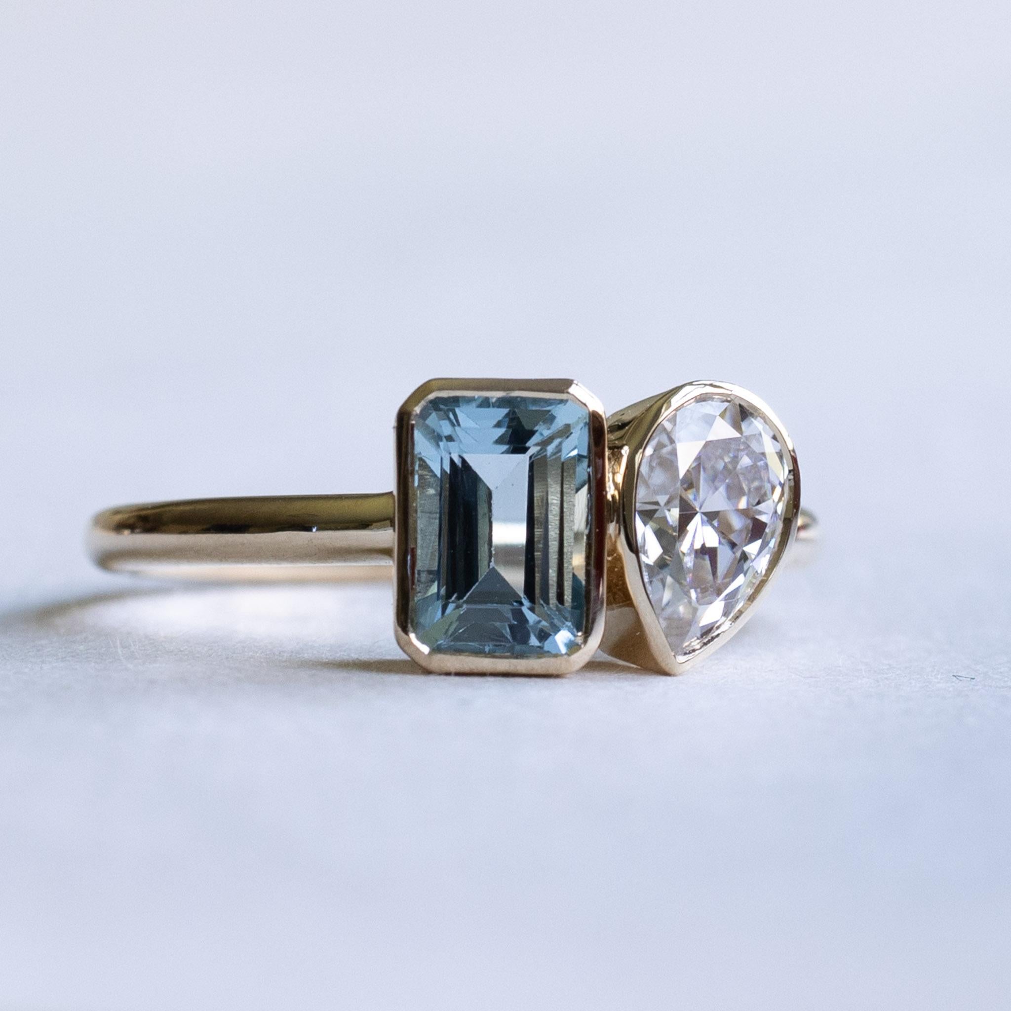 Emerald cut aquamarine with pear moissanite on this you and me ring.

Metal: 14k Gold
Stone 1: Aquamarine
Stone Shape: Emerald cut
Stone Size:  5mm x 7mm
Stone 2: Moissanite
Stone Shape: Pear
Stone Size: 5mm x 7mm
Color: DEF
Forever One Charles and