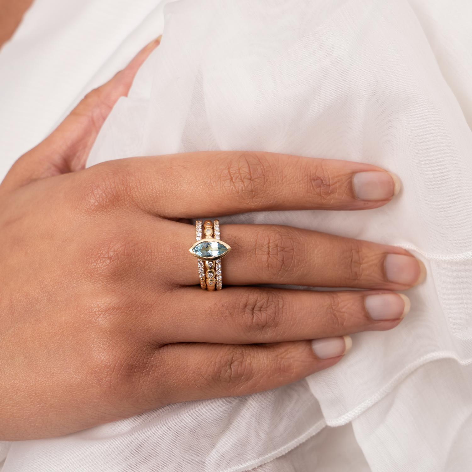 One of our dramatic signature styles, the Bubbles of this 14k yellow gold ring circle the finger with small diamonds flush set at the front and a cup set marquise cut Aquamarine rising above. Wear it alone for a minimalist look or stack with other