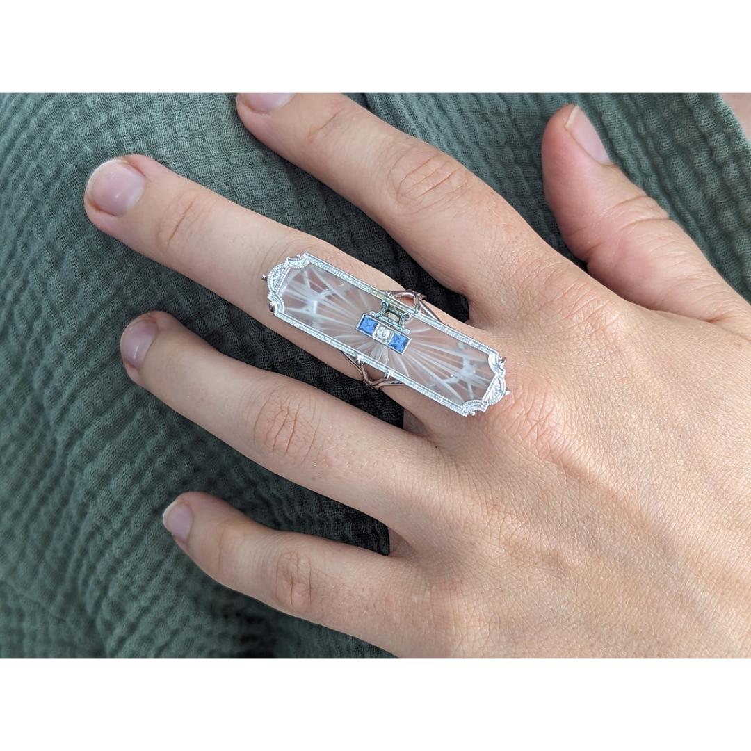 Vintage from the 1930s
Materials: White gold
Gemstone: Diamond
Gem Color: Black
Band Color: Gold

Style: Art deco

Beautiful Art Deco ring made before the first half of the century.

Frosted Camphor glass with center diamond and princess sapphires.