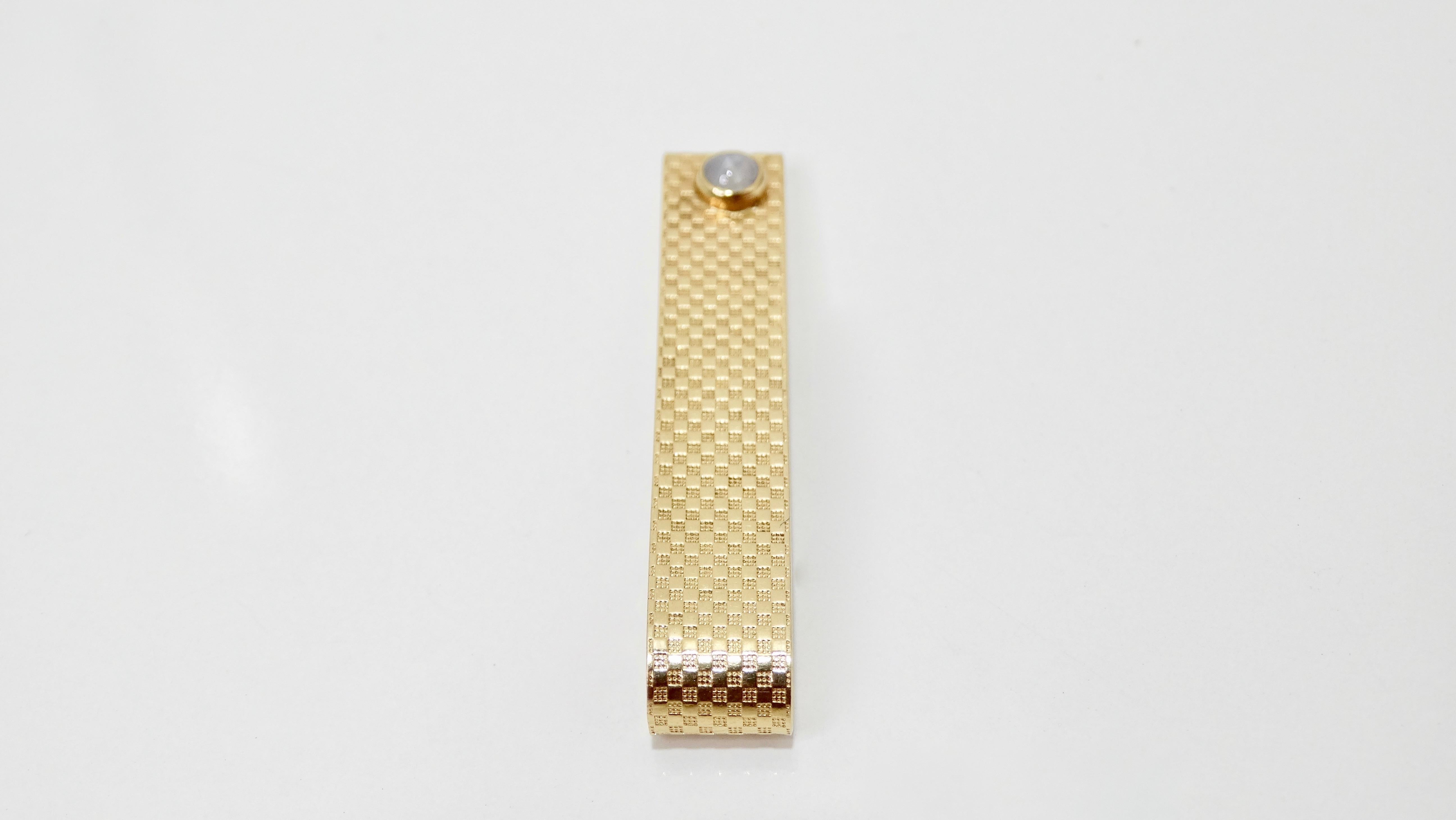 Elevate your tie with this timeless tie clip! Circa mid 20th century, this tie clip is crafted from 14k gold and is embossed with a textured checkered pattern. Features a gorgeous star sapphire and a slide closure for secure wear. Total weight is