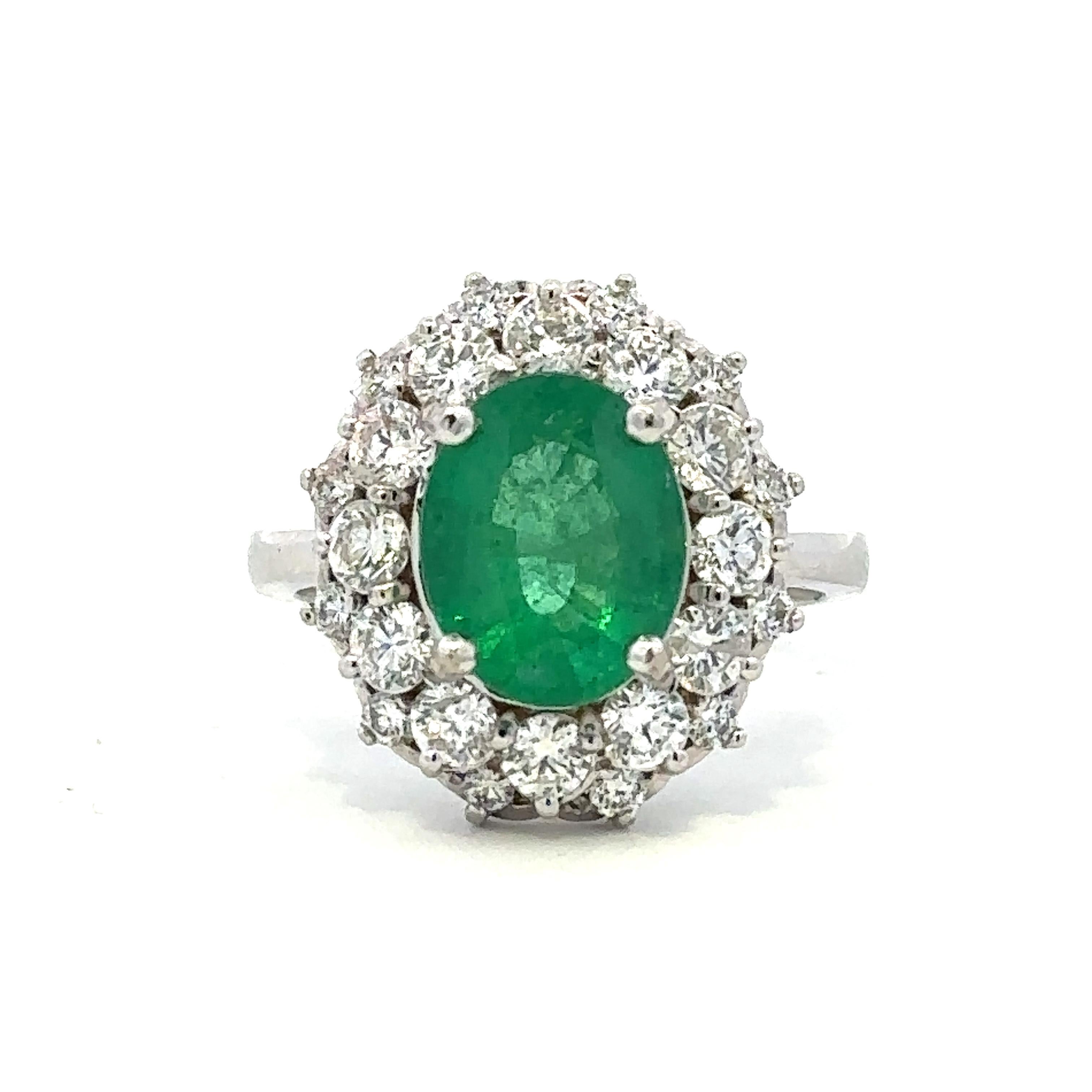 A stunning oval cut Colombian emerald set within a striking halo of round brilliant diamonds in 14k white gold. The emerald weighs approximately 3.5 cts and has moderate oil treatment. The diamonds have exceptional radiance, with SI1 clarity and G-H