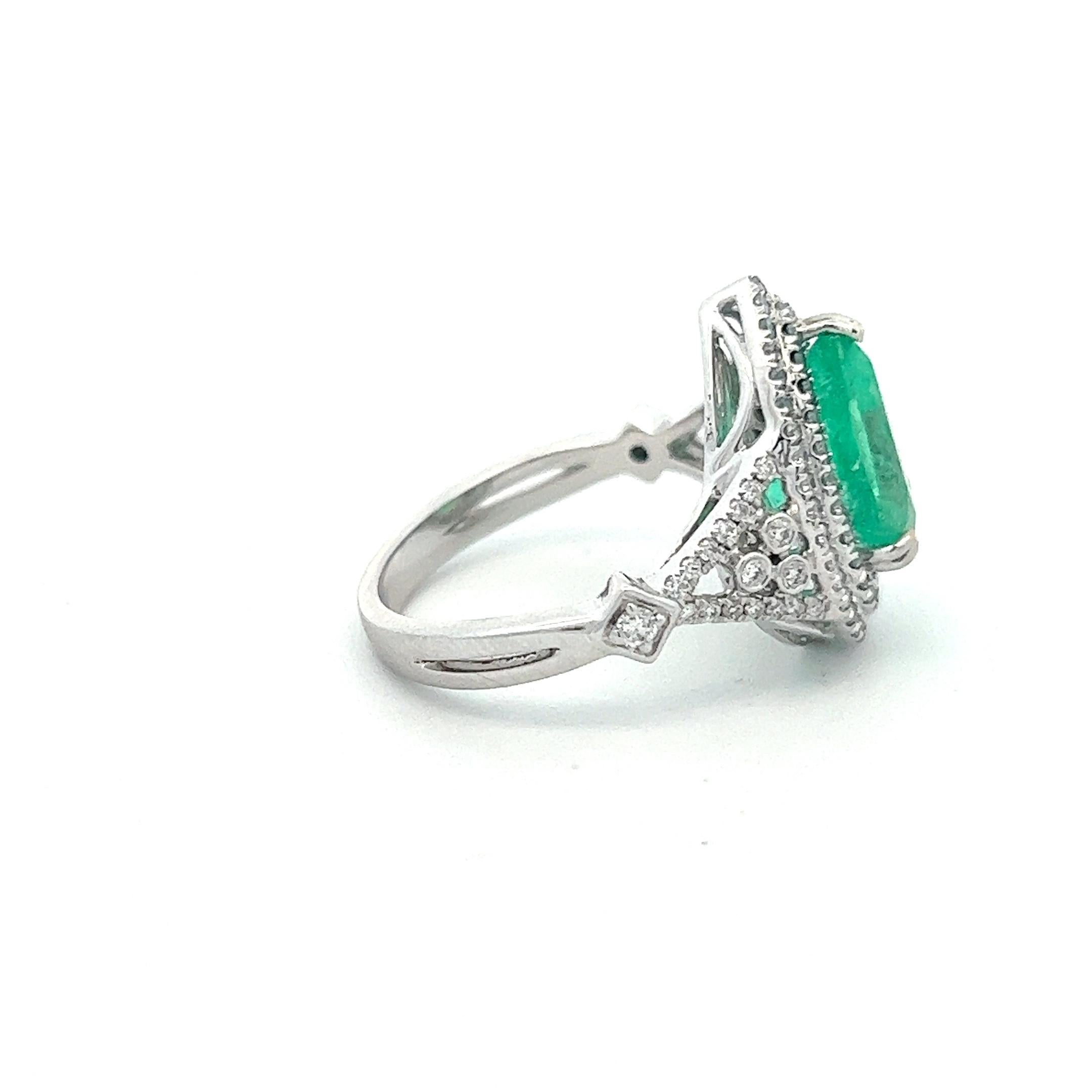 A striking presentation of an exceptional Colombian emerald within a double halo of diamonds in 14k white gold. The emerald, measured in setting, weighs approximately 2.88 carats, and has a few very minor chips and abrasions visible under