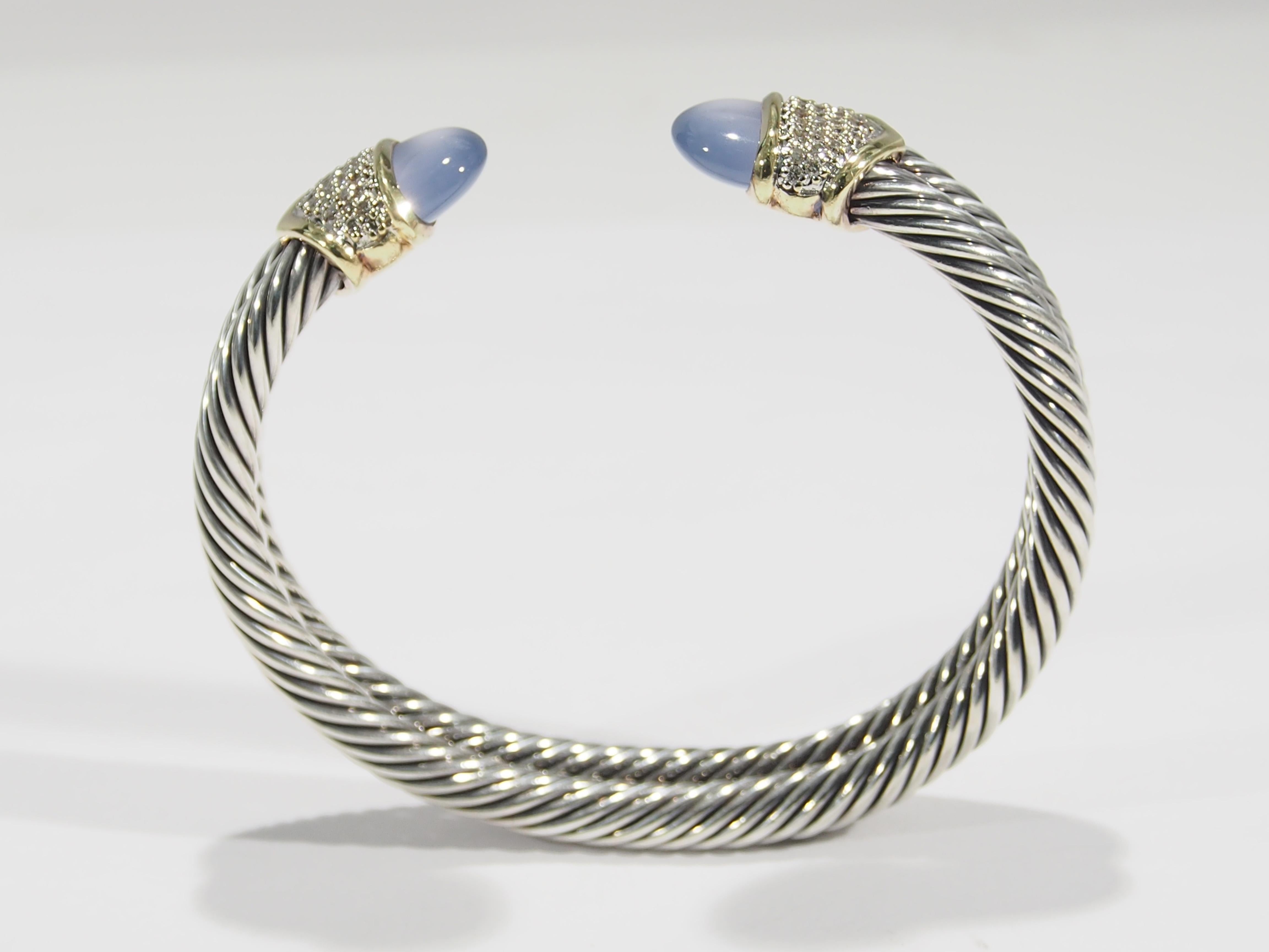 A David Yurman Sterling Silver and 18k Yellow Gold Diamond Blue Chalcedony Double Cuff. This stunning Cuff bracelet is crafted of sterling silver cable style hoops accented by symmetrical blue Chalcedony stones set in gold collars studded with Pave