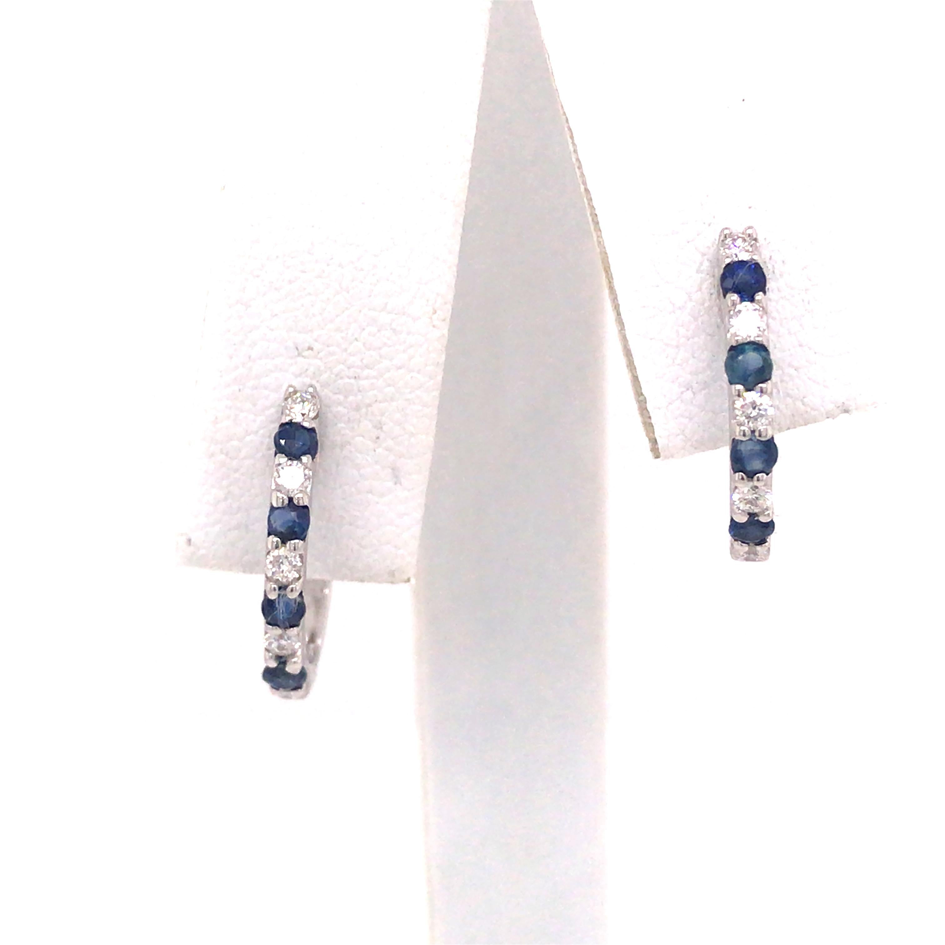 Diamond and Sapphire Huggie Earrings in 14K White Gold.  Round Brilliant Cut Diamonds weighing .18 carat total weight, G-H in color and VS-SI in clarity are expertly set alternating with Sapphire Gemstones.  The Earrings measure 5/8 inch in