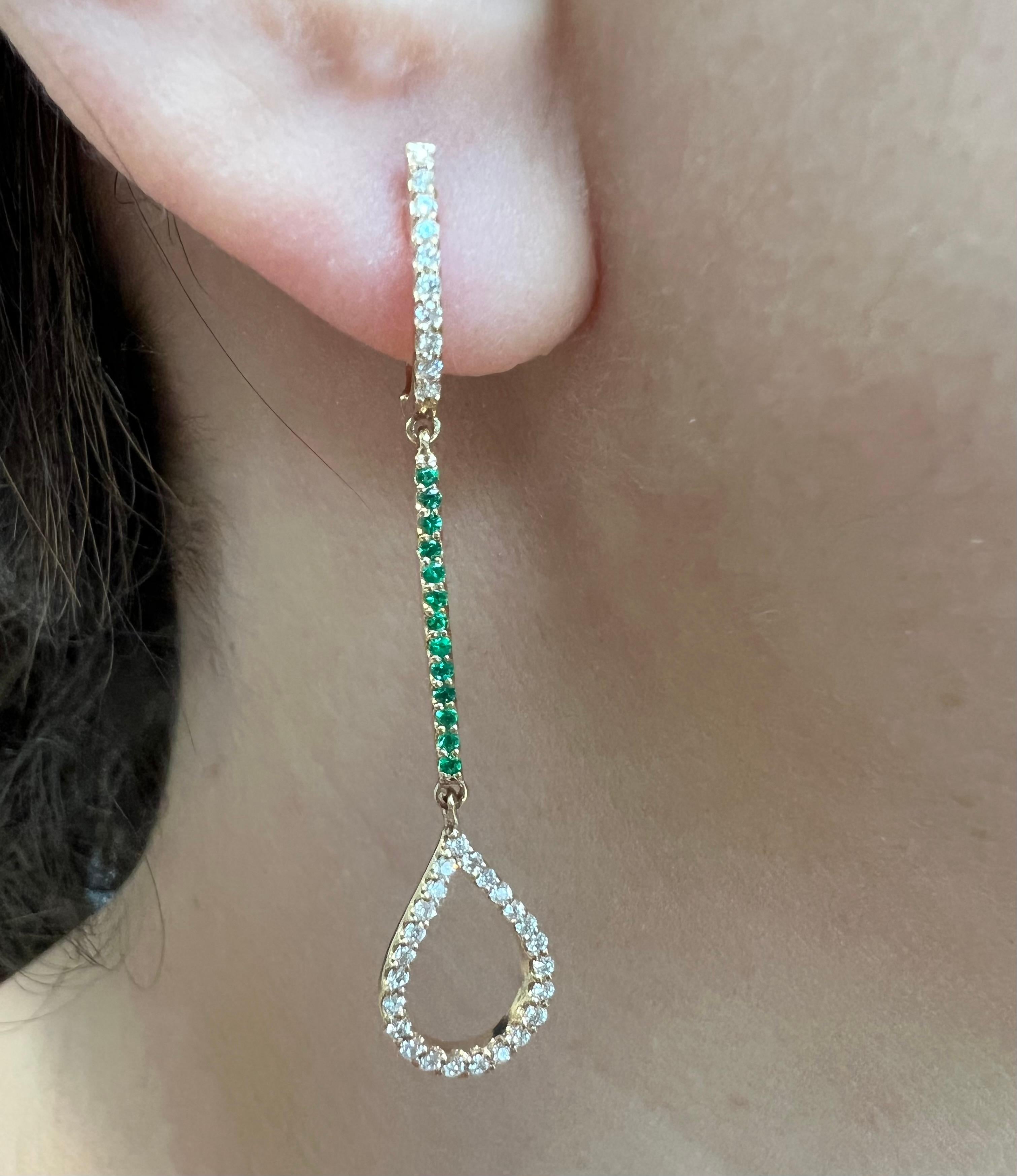 Crafted in 14K yellow gold this stunning dangle earring takes the form of a teardrop, with a whole host of deep green emeralds and shimmering round diamonds delicately lining its form. Lightweight, yet still a major statement piece, this earring is