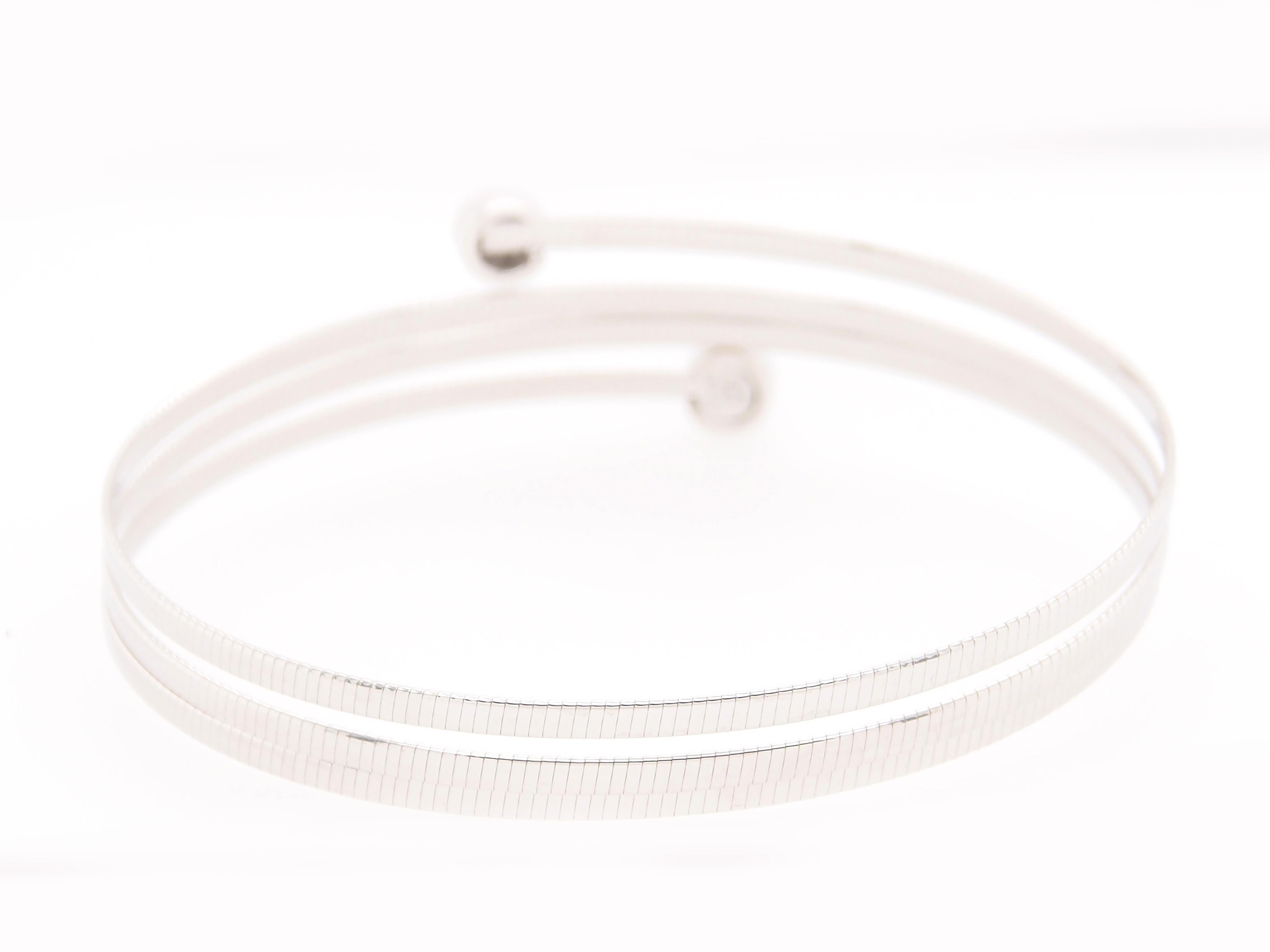 This is a great 14K White Gold 4 Band Wrap Bracelet with Diamond Bezel Ends. Set with (14) Round Brilliant Cut Diamonds G-H in color, VS-SI in clarity and approximately 0.14 carat total weight. A delightful Bangle that is flexible and wraps