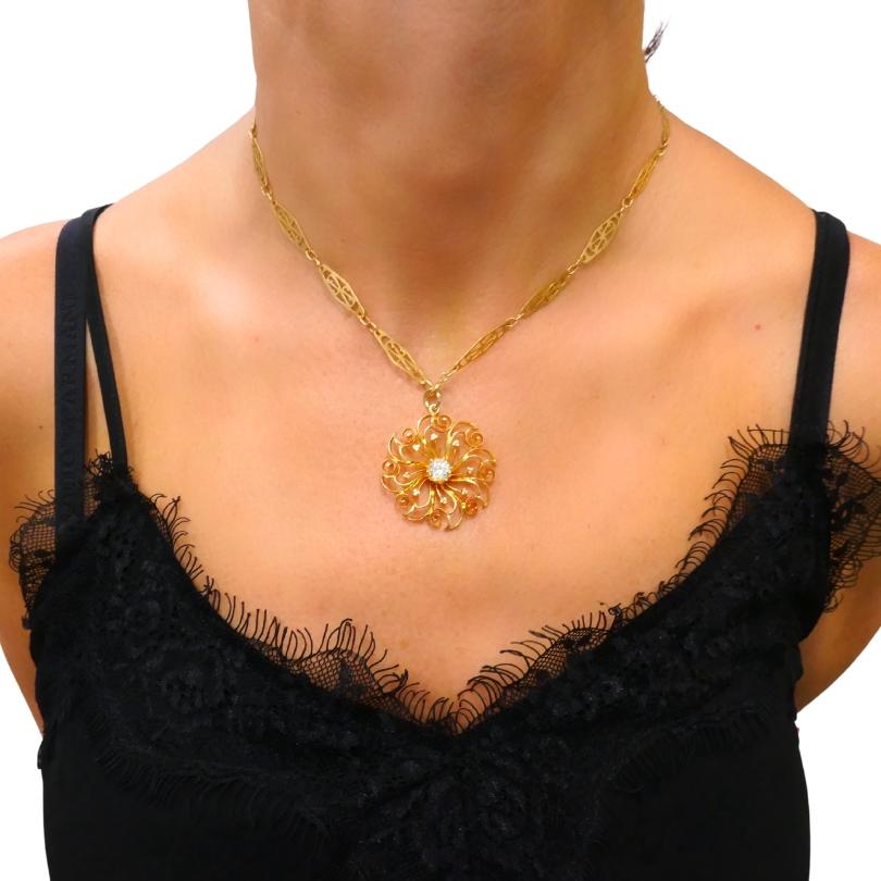 Un'affascinante collana dell'inizio del XX secolo con una delicata catena in filigrana d'oro 18 carati, abbinata ad un paio di fili d'oro.  Ciondolo traforato in oro 14k con motivo floreale, accentuato da una  diamante al centro. Il design a spirale