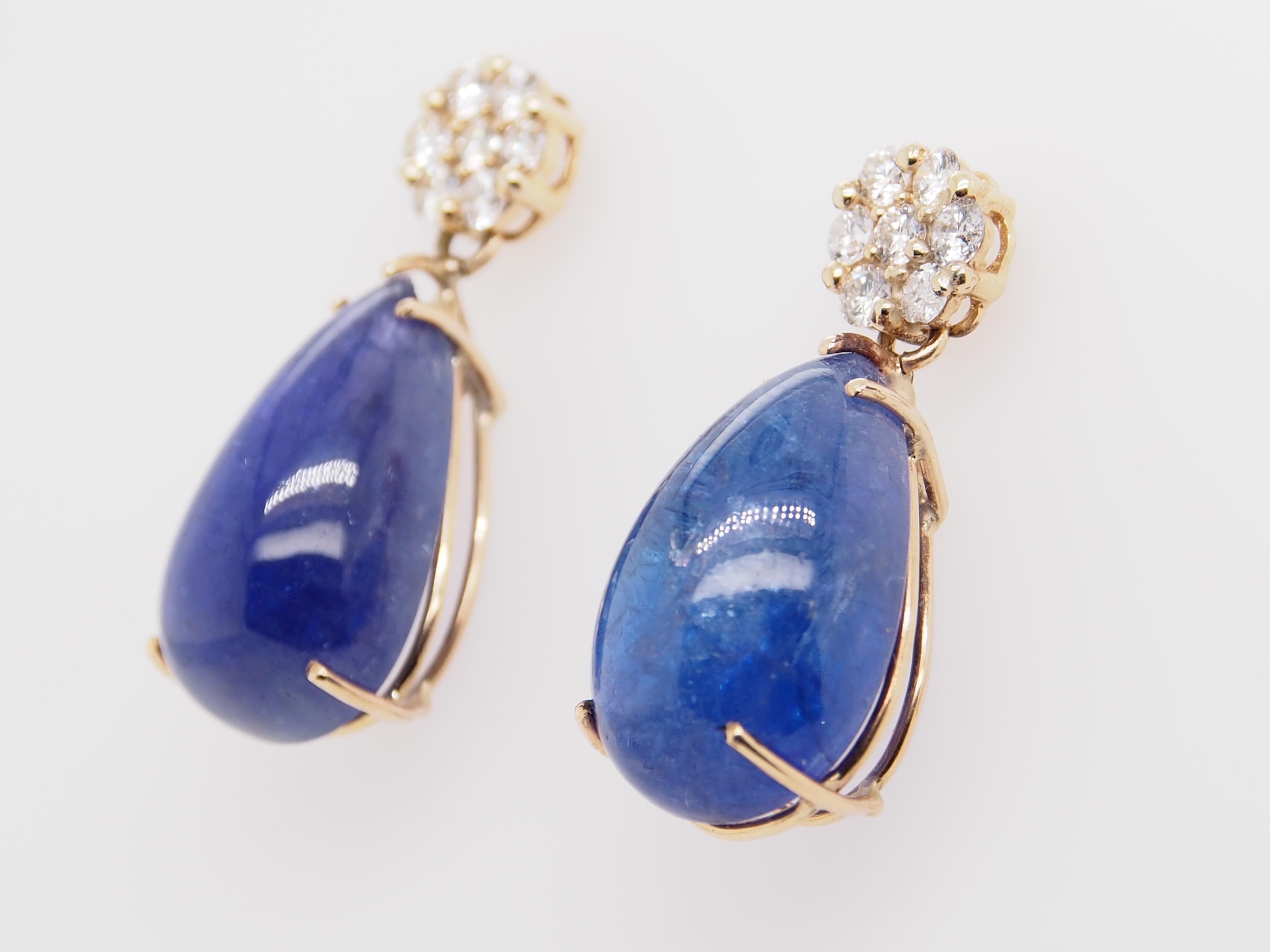 A stunning pair of 14K yellow gold earrings. A beautiful Tanzanite stone dangles from diamond flower cluster. Each Tanzanite measures 20.5x12.2x9, approximately 36 carat total weight. (14) Round Brilliant Cut diamonds G-H in color, VS-SI in clarity
