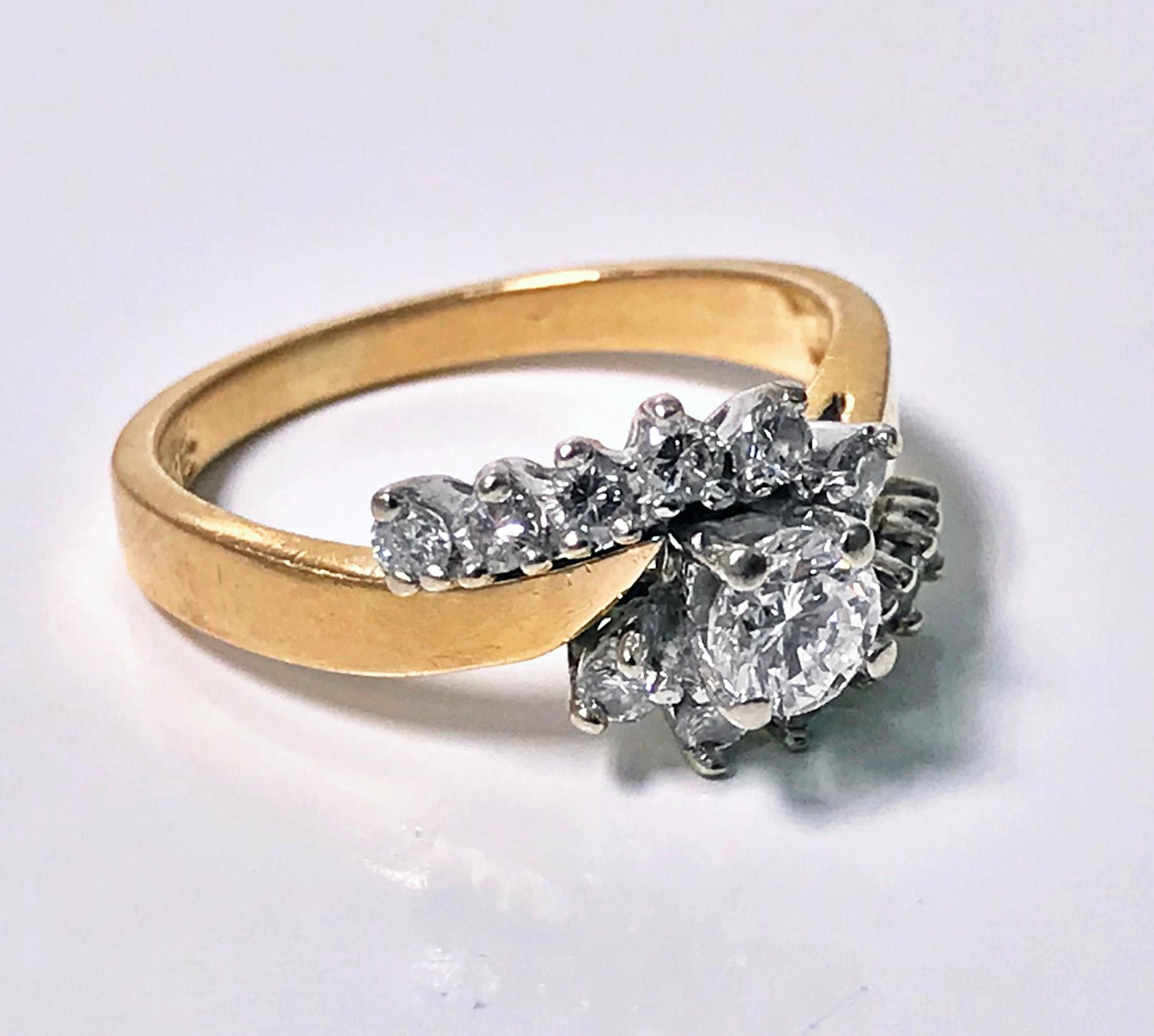 Diamond twist design 14K Ring. The ring centering a round brilliant cut diamond, approximately 0.30 ct, approximately VS1 clarity, approximately H colour, flanked with off set twist, set with 12 full cut diamonds, total diamond weight approximately