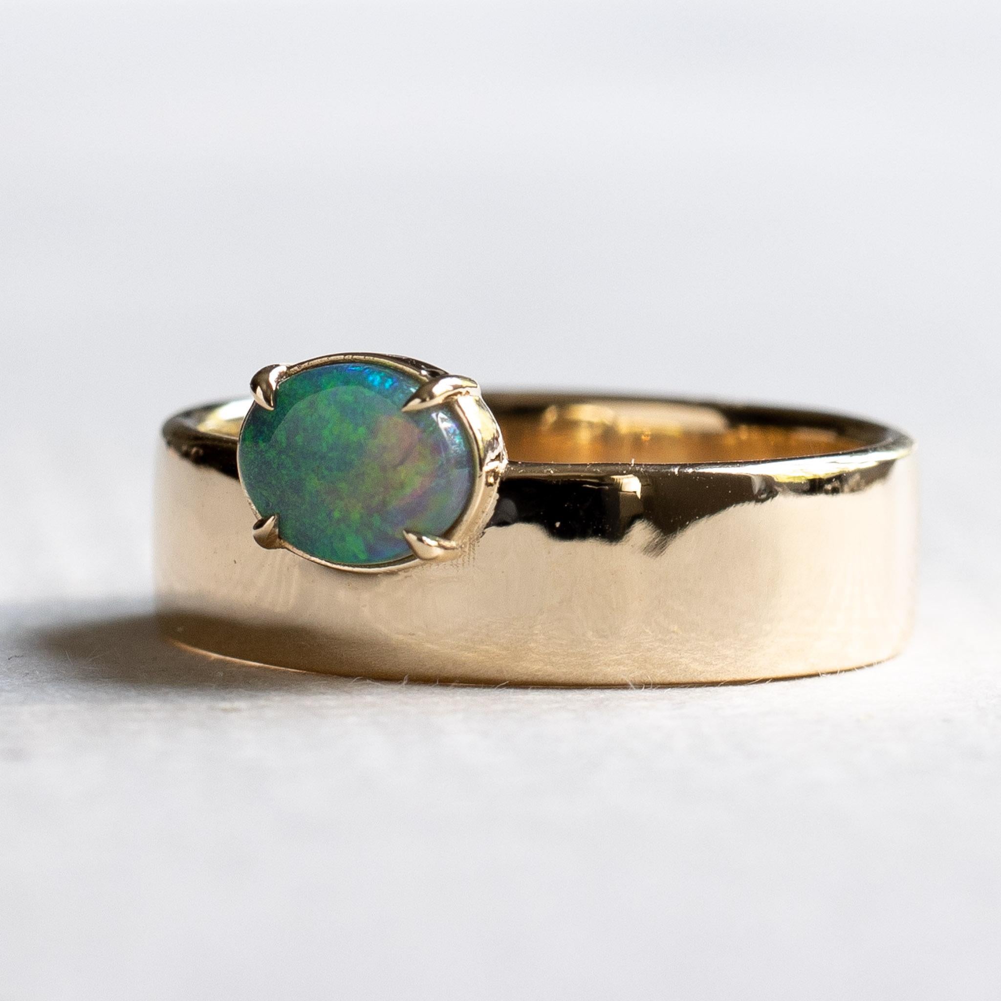 Off-set east west oval opal ring set on 14k yellow gold band. 

Metal: 14K Yellow Gold
Stone: Australian Opal
Stone Shape: Oval 
Stone Size: 6mm x 8mm
Band Width: Approx 5.5mm x 1.25mm