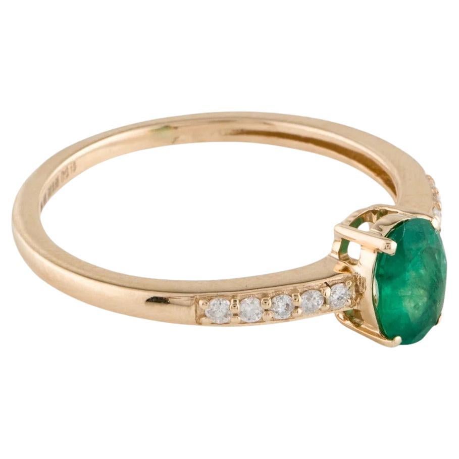 This elegant 14K Yellow Gold Cocktail Ring showcases a stunning 0.65 Carat Oval Emerald, exuding timeless sophistication. Complemented by 10 Round Brilliant Diamonds with a total carat weight of 0.13, this piece adds a touch of sparkle to any