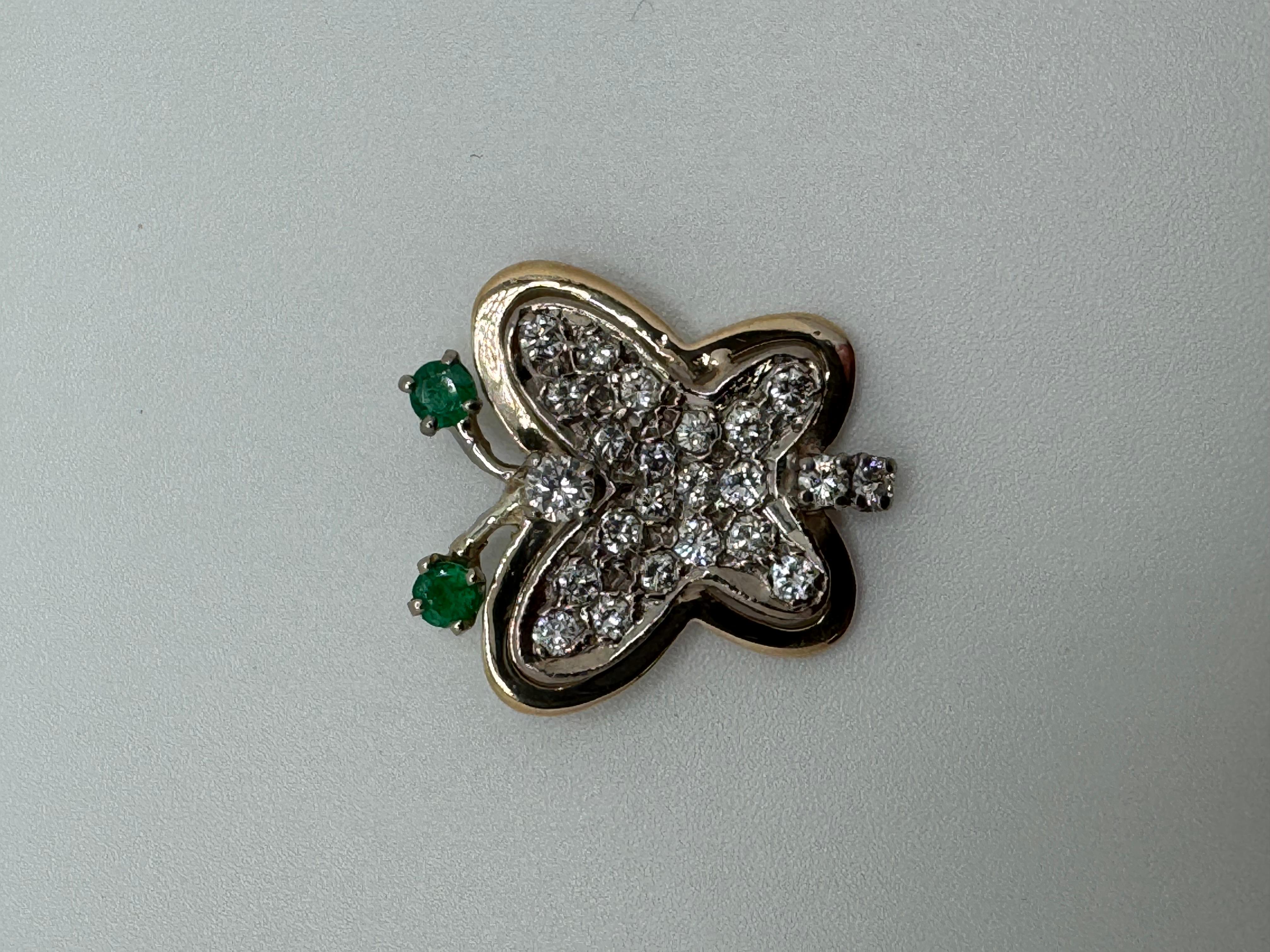 Questo elegante ciondolo a farfalla bicolore è realizzato in oro bianco 14 carati e ornato da gemme vibranti. Gli occhi della farfalla sono caratterizzati da due smeraldi verdi, che aggiungono un accento morbido e suggestivo al design. 23 diamanti