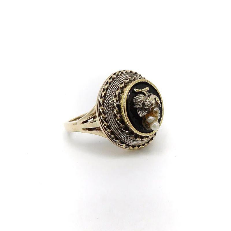 This is an exquisite Etruscan Revival mourning ring with 14k gold and an onyx disc and grape cluster made with pearls. There is a repeating motif of twisted wire around the black circular onyx. This detail adds nice texture and glisten to the