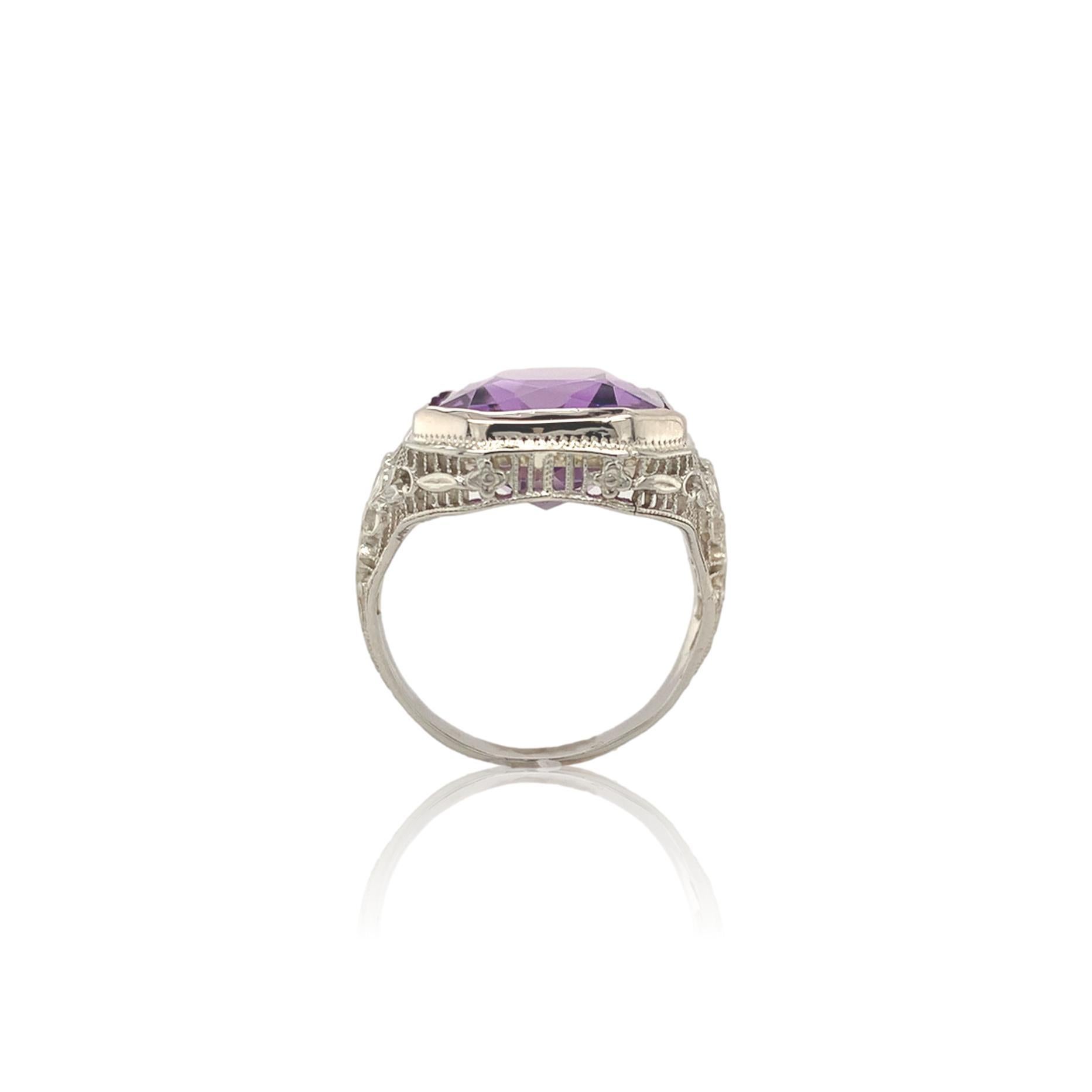 14K white gold filigree Art Deco ring featuring a large amethyst weighing 7.90 carats. This is the original stone, newly polished in the same rectangular brilliant cut, measuring about 13.5mm x 12mm. The stone s a bit deep for the ring. The ring