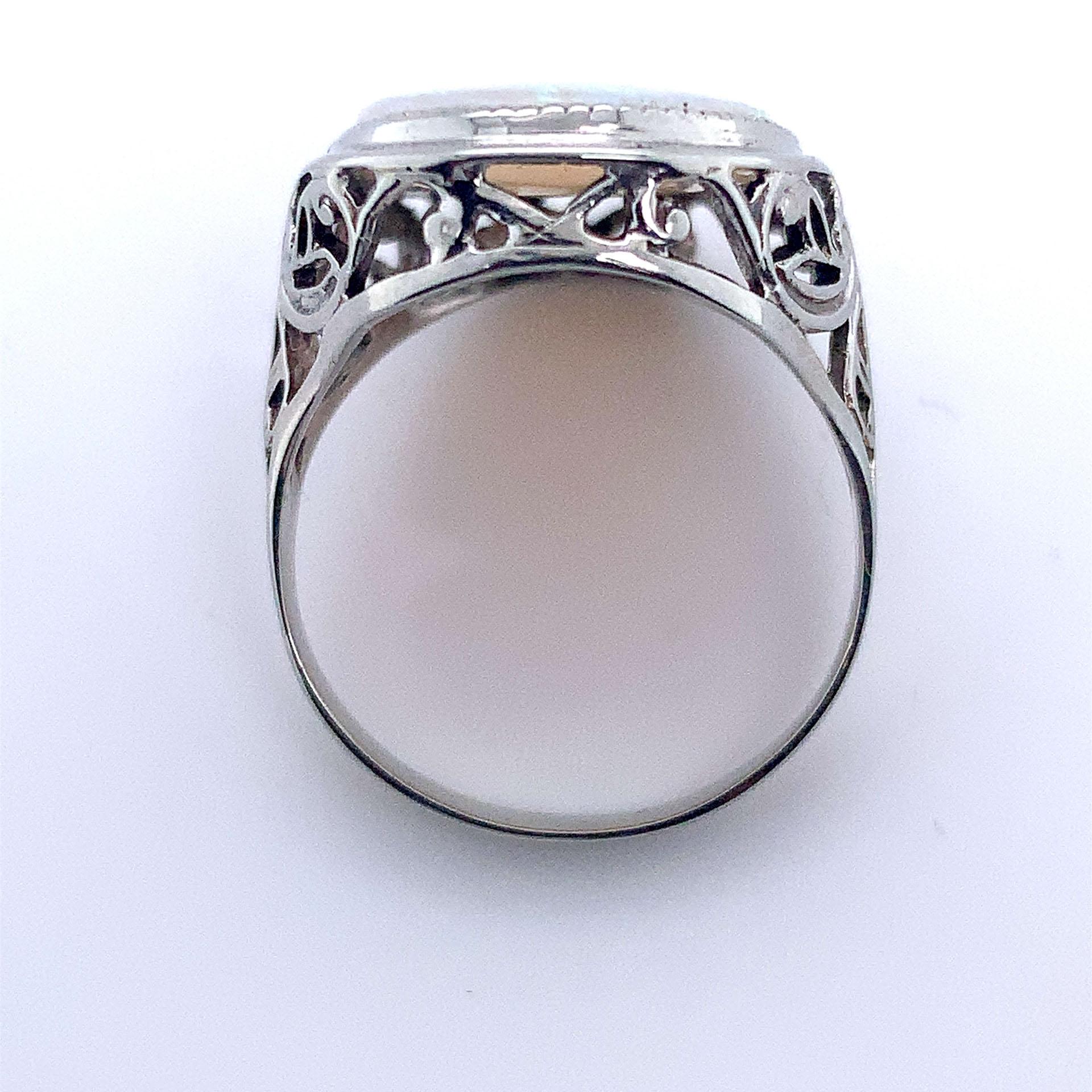Art Deco 14K white gold filigree ring featuring a large oval cabochon opal weighing 4.70 carats. The genuine opal measures about 18.5mm x 14.5mm and has blue green play of color.  The ring fits a size 7 finger. It weighs 2.8dwt and dates from the
