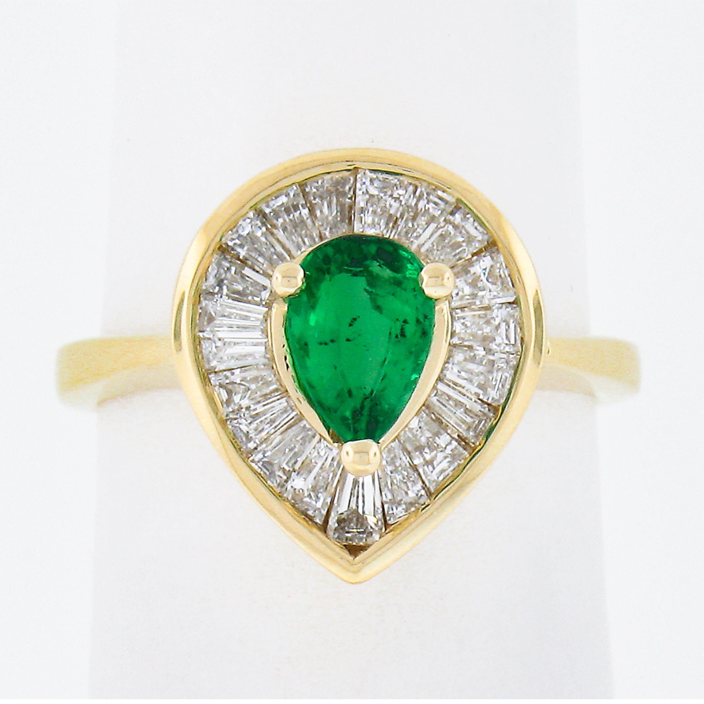 This is an absolutely beautiful ballerina ring that is crafted in solid 14k yellow gold featuring a gorgeous and high quality emerald solitaire surrounded by a fiery diamond halo. The prong set pear cut emerald stone stands out with its very vivid