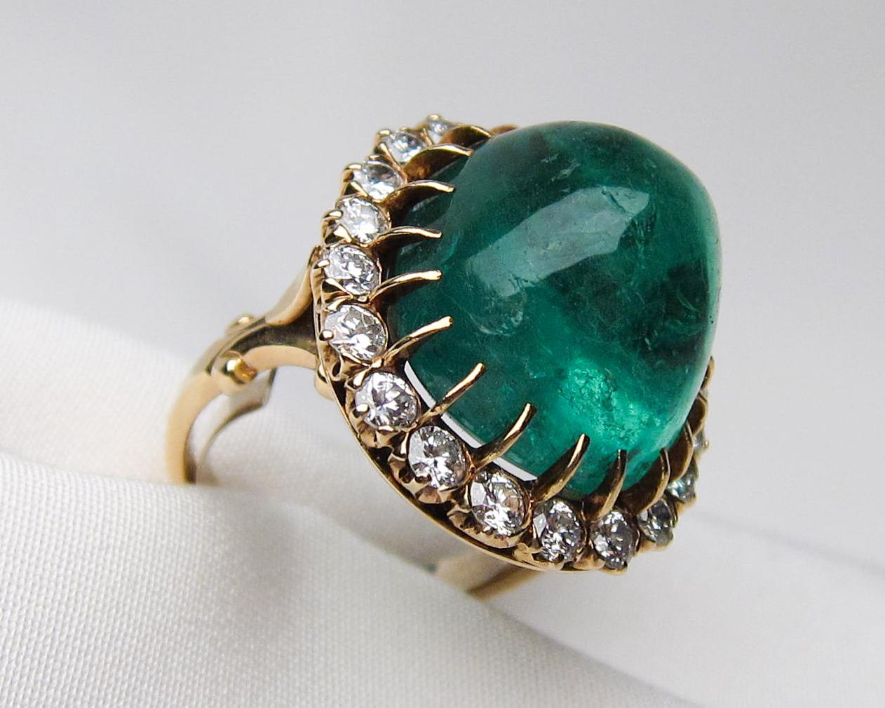 Circa 1940. This fabulous Retro Era ring features a dazzling 27.60 carat cabochon-cut natural emerald, surrounded by twenty prong-set round brilliant-cut diamonds, set in 14KT yellow gold. The diamonds weigh 1.60 carats with an SI1-SI2 clarity and