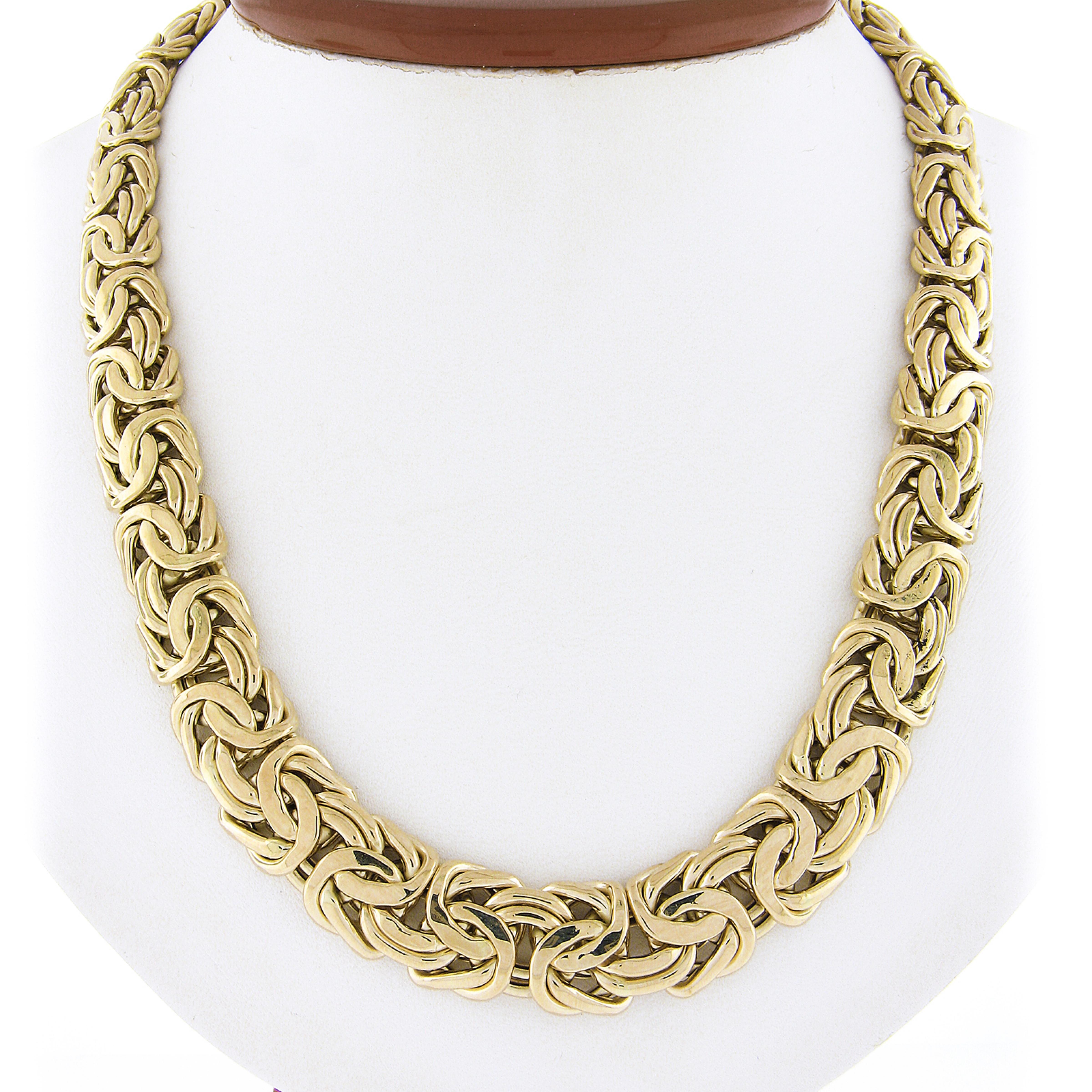 This well made Italian made byzantine link chain necklace is crafted in solid 14k yellow gold. The necklace measures 18 inches in length, graduates from 10mm to 14.8mm in width, with a flat and domed style giving it a nice bold look around the neck.