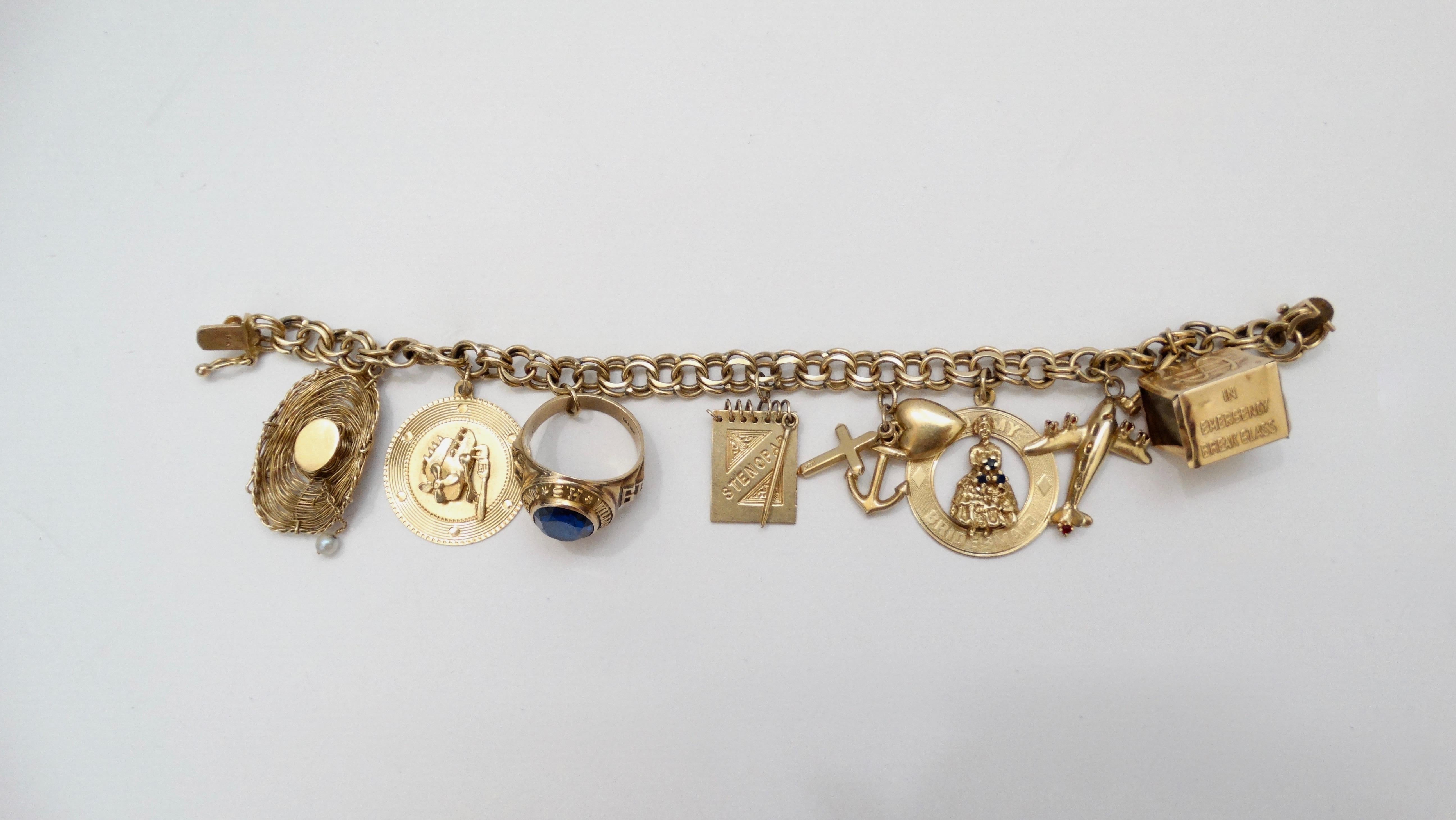 Gorgeous 14k Gold charm bracelet from 1950s/1960s. Bracelet features a variety of eight 14k Gold charms encrusted with pearls, ruby and sapphire including a cowboy hat, class ring, airplane, money box, a bridesmaid and a cluster of a cross, heart