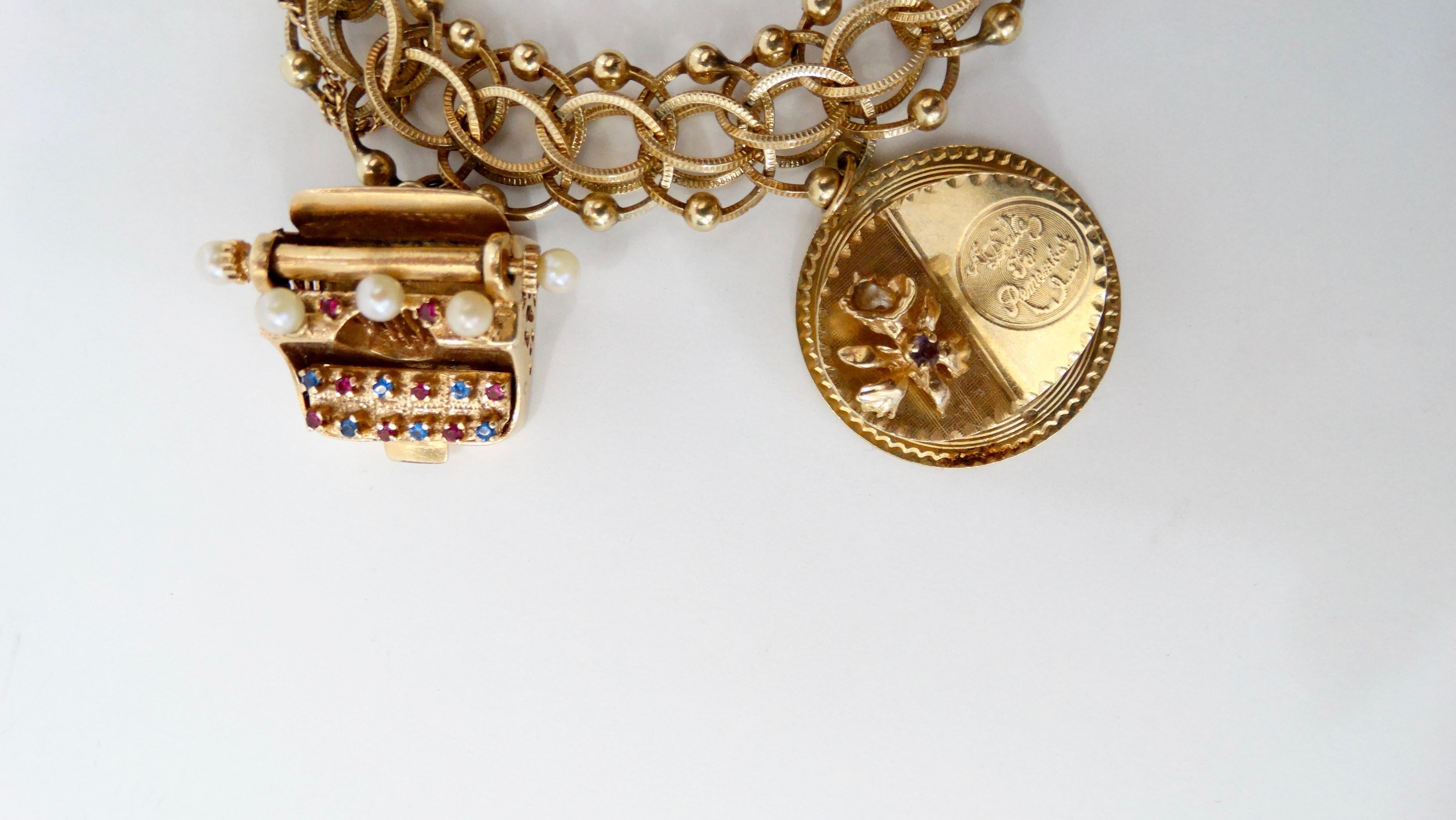 Gorgeous 14k Gold charm bracelet from 1959. Bracelet features a variety of five 14k Gold charms encrusted with pearls, ruby, emerald, amethyst and sapphire including a type writer, Merry Christmas charm, and Cherub Angel. Bracelet features a