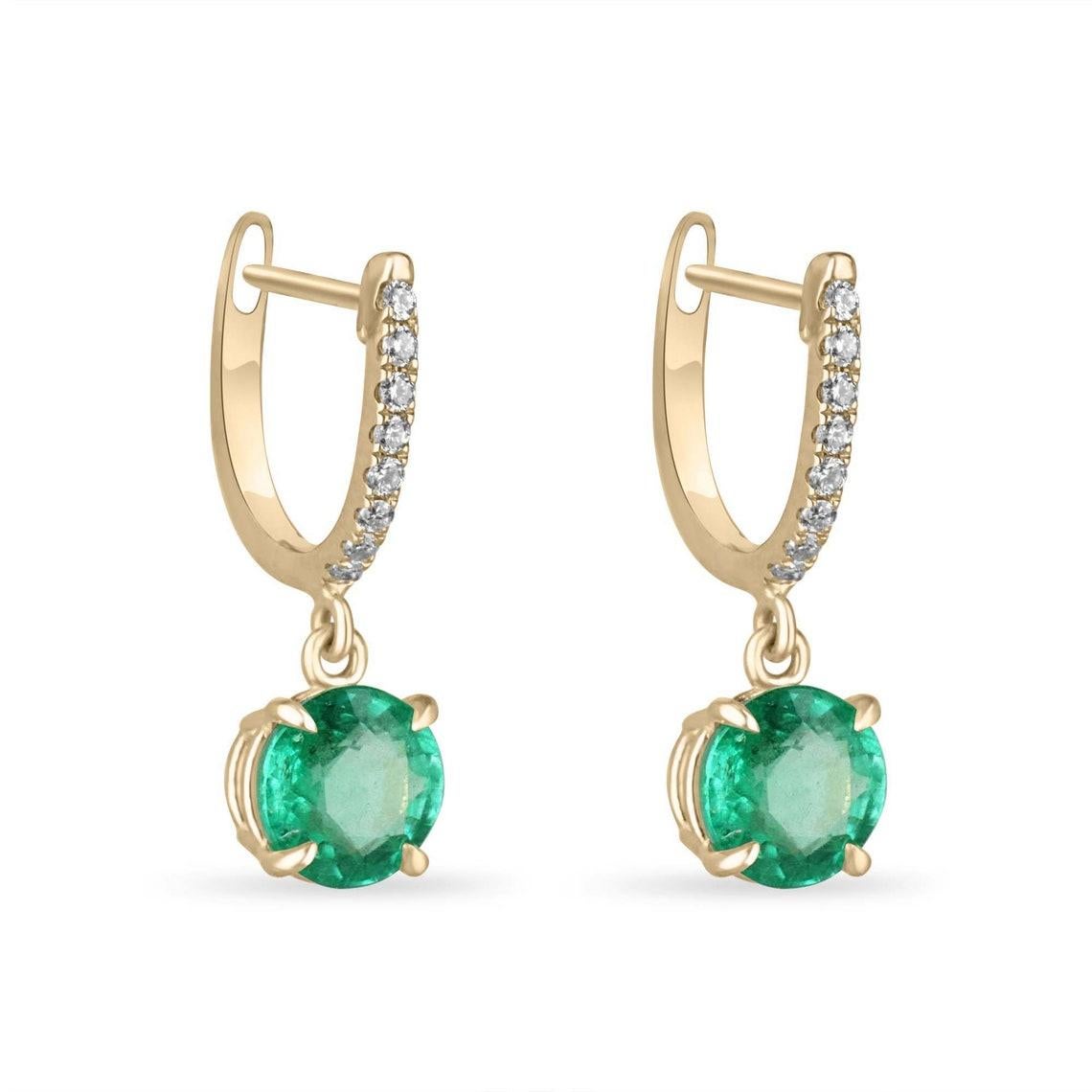 Eleva il tuo stile con i nostri squisiti orecchini a pendente con smeraldo, una miscela armoniosa di bellezza naturale e design moderno. Due smeraldi a taglio rotondo, per un totale di due carati e mezzo di peso complessivo, penzolano con eleganza
