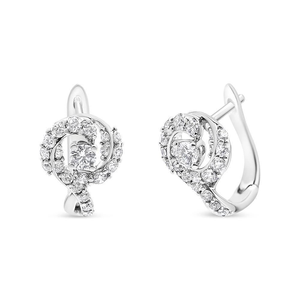These gorgeous diamond halo earrings feature stunning round diamonds embraced by a glittering halo of pavé-set diamond accents. Pavé diamonds shimmer down the front of the earrings for added sparkle. These huggy hoop earring secure with a lever